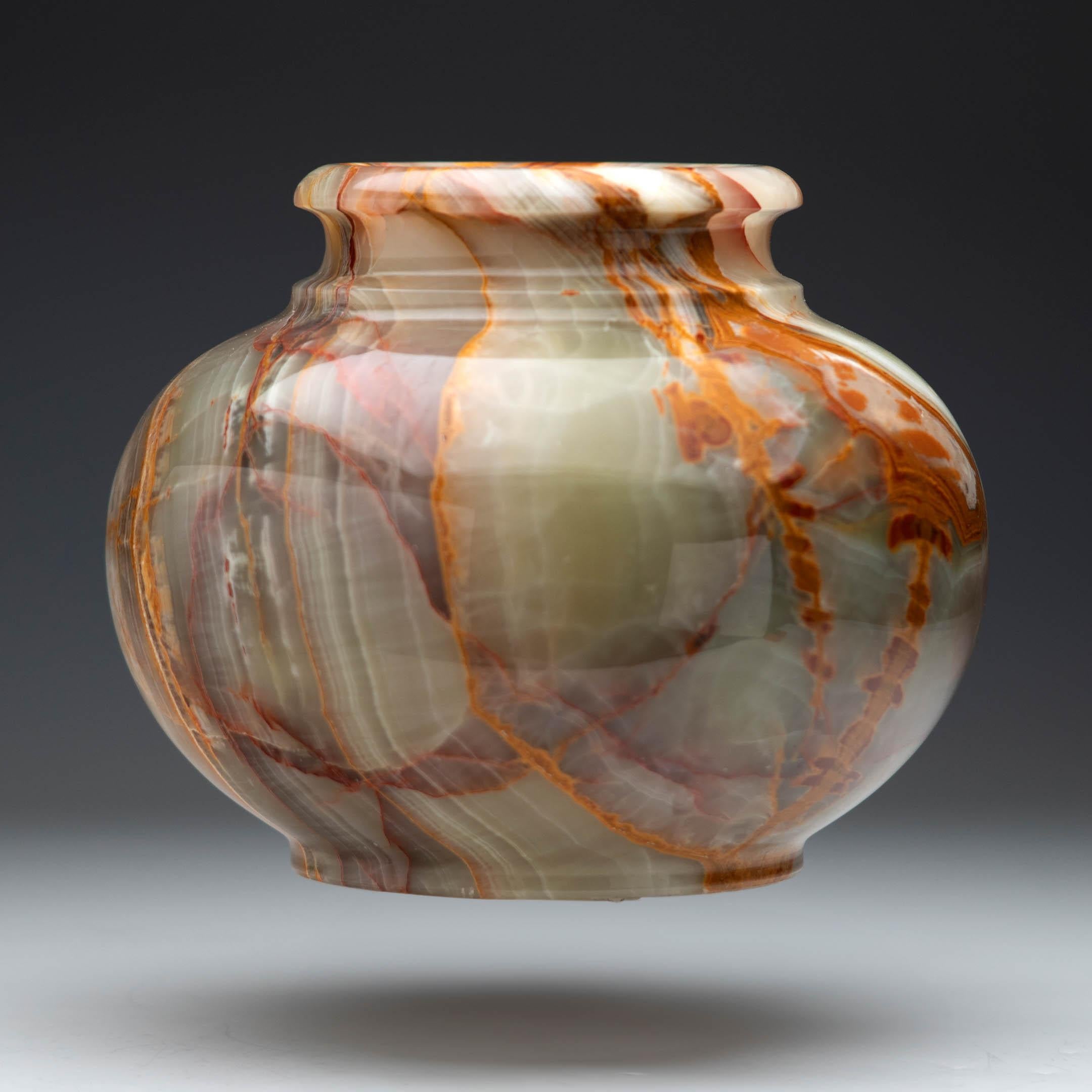 This hand-polished Banded Onyx vase showcases the timeless elegance of natural stone artistry. Hand-carved and expertly finished, it glows with bands of warm cream, earthy rust-red, and soft olive. Each hue swirls together in striking harmony. Every