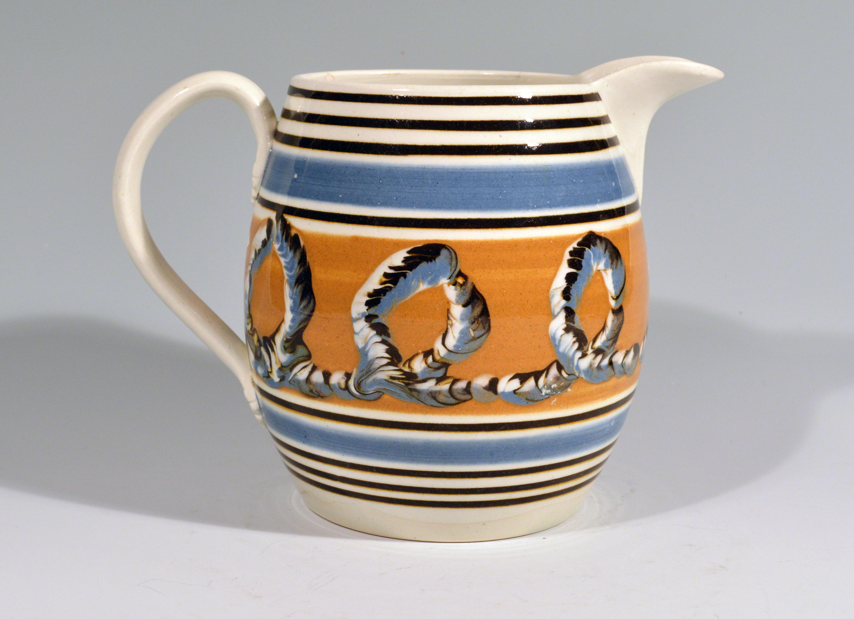 Banded pearlware mocha jug with Earthworm design, 
1790-1810.

The barrow-form jug has a wide central band of ochre decorated with a three-color earthworm design. Above and below are a series of line in blue and brown. The loop handle with leaf