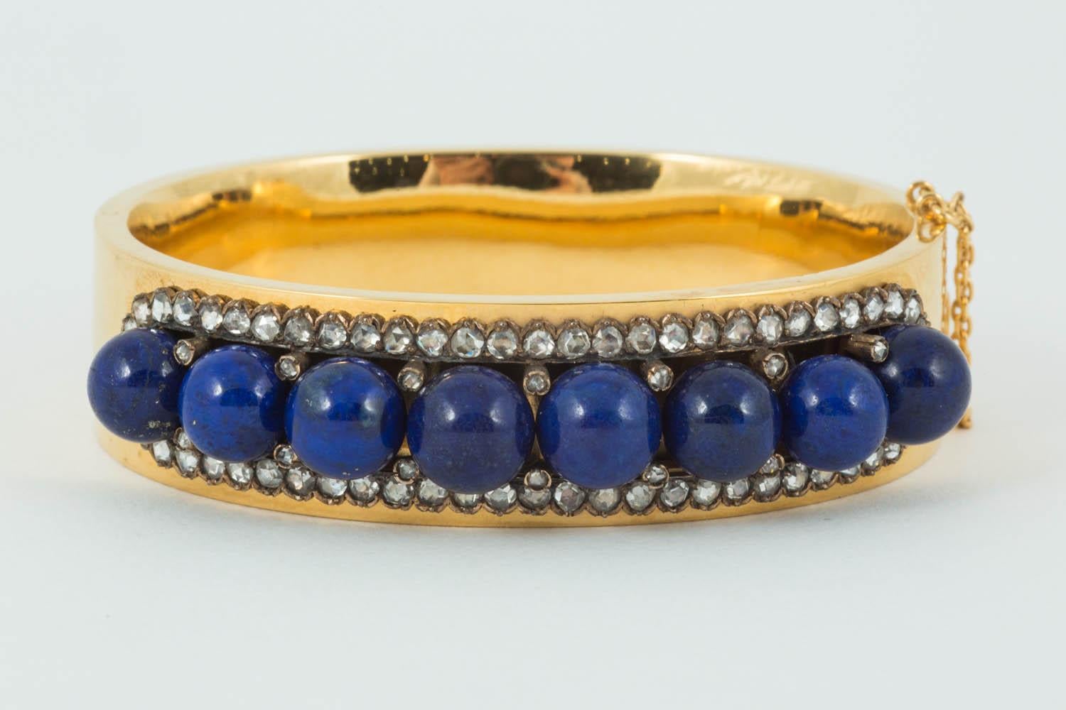A finely made 18ct yellow gold half hoop bangle set with eight,lapis lazuli beads of natural colour with rose cut diamonds surrounding and in between French marks to the tongue, 18mm wide,50mm inside depth.C 1910