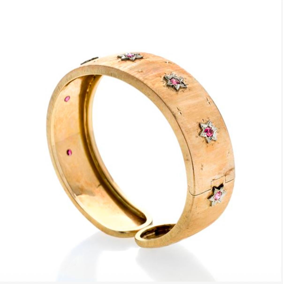 Bracelet bangle de style florentin en or jaune gravé, orné de sept étoiles, chacune avec un petit rubis. Le bracelet peut être ouvert pour s'adapter au poignet.
Fabriqué en Italie, à Florence, dans les années 1990
MESURES : diamètre intérieur 6 cm
