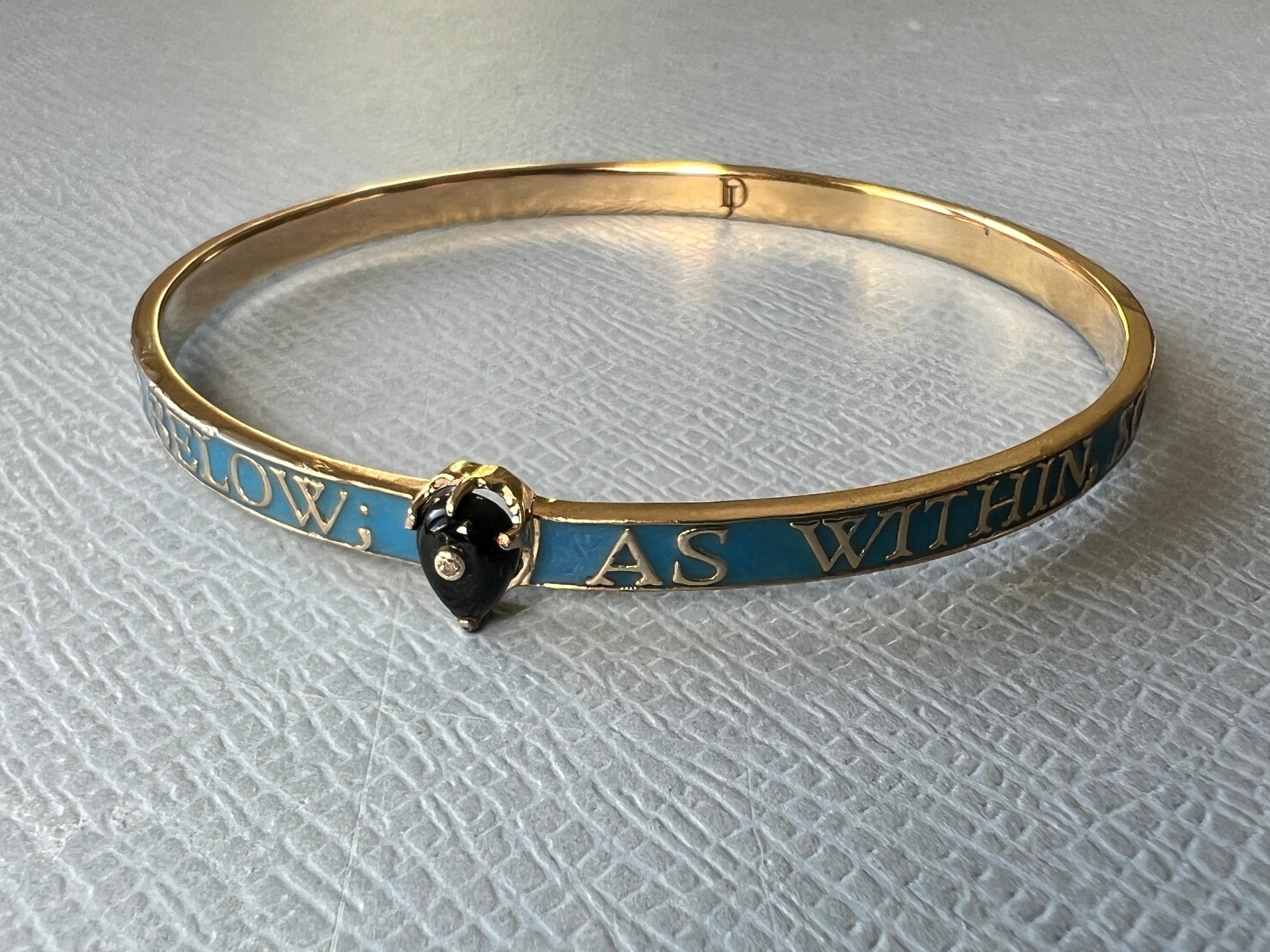 Bangle Bracelet 14K Gold, with light Blue Enamel,  It has a heart Onyx with a pierced mini Diamond

The text on the bracelet say: For we walk by faith - not by sight.

Designer J Dauphin

There is an image on the bangle worn, but the color is not