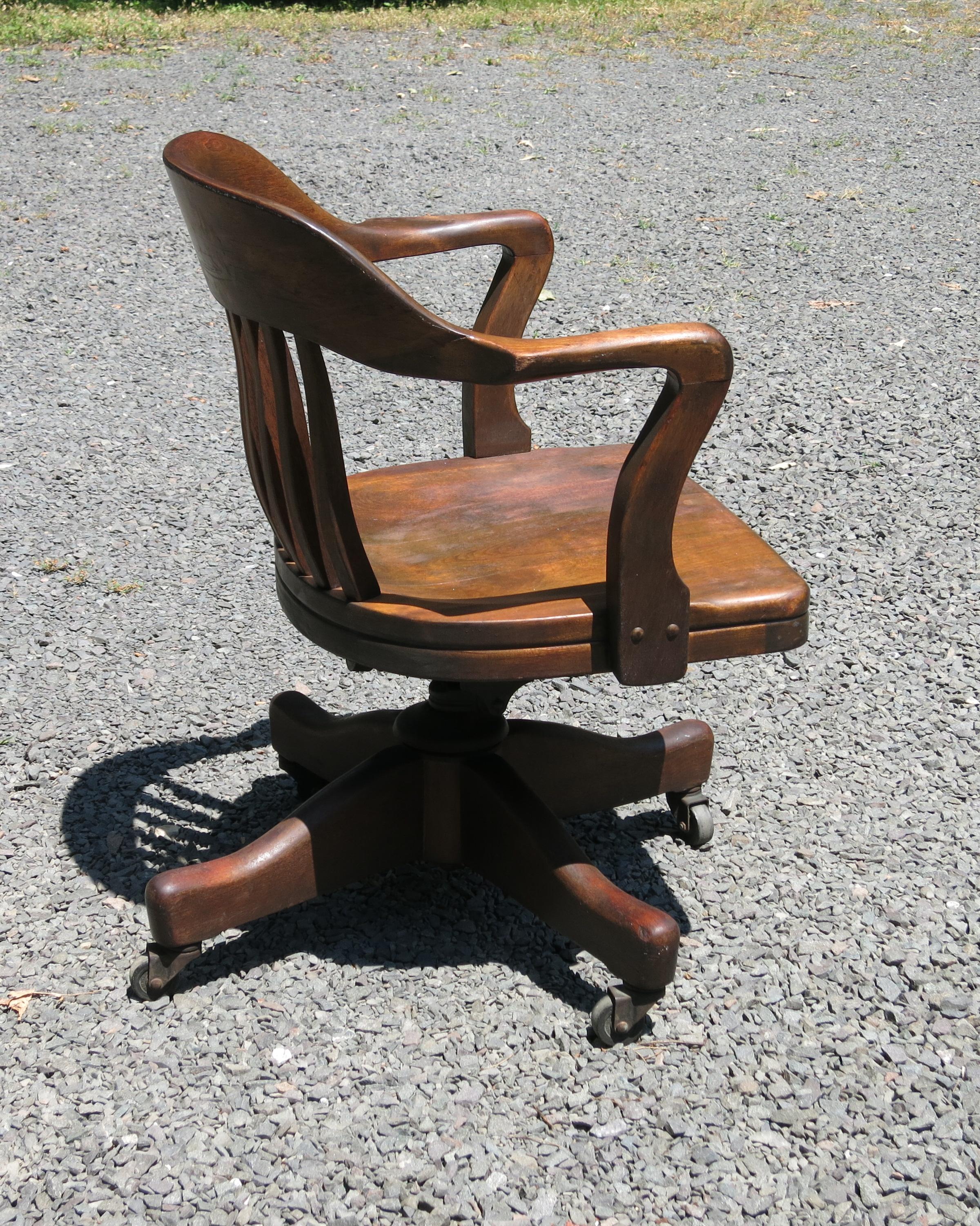 Bankers swivel chair adjustable and on wheels. Worn finish with warm patina. Some scratches and chips. Adjustable for tilt and height. It is 24.5