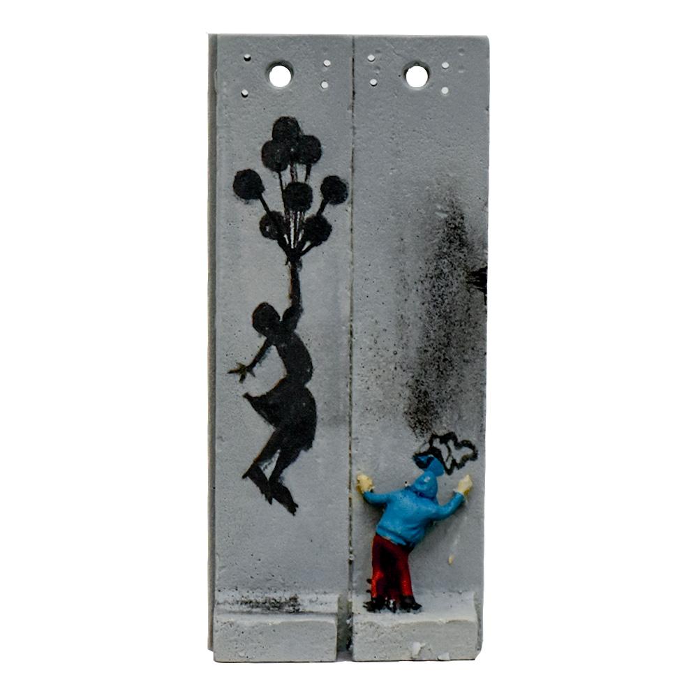 Scultura che raffigura la nota immagine della Flying Balloon Girl dipinta sul muro di separazione da Banksy nel 2005.
Conosciuto anche come Ragazza con i palloncini.
Si tratta di una scultura murale in due parti con una piccola figura che dipinge i