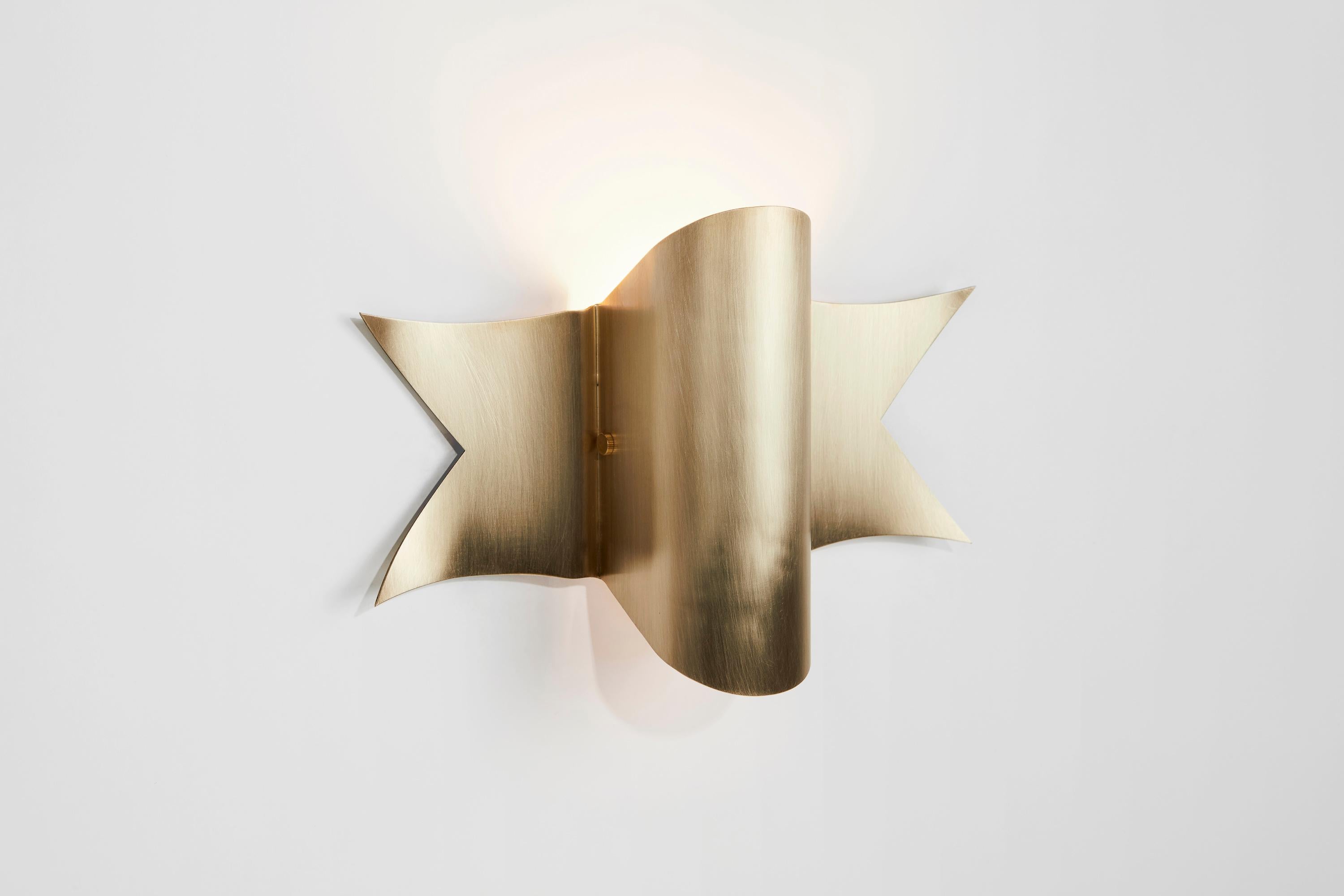 Banner reimagines the ribbons depicted in classic 1930s and 40s military tattoos. This fabric form replicated in a stainless steel sconce captures a tension between the masculine and the feminine. Banner is offered in stainless steel or solid brass