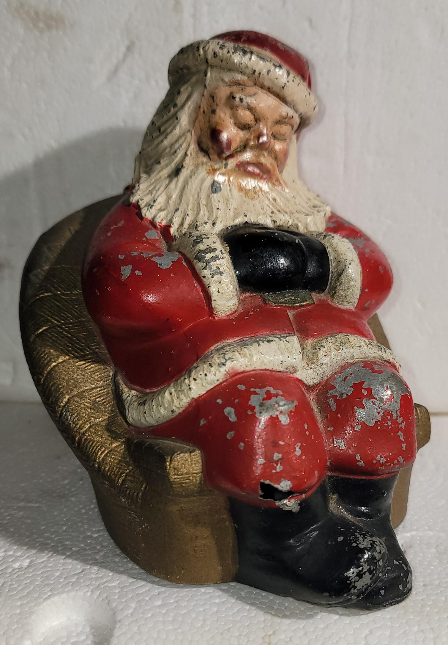 Banco di Babbo Natale in metallo dei primi del Novecento. Babbo Natale seduto su un sedile ad ala dopo una dura giornata in slitta. Banco di monete originale dipinto. Meravigliosa patina sul corpo Grande colore.