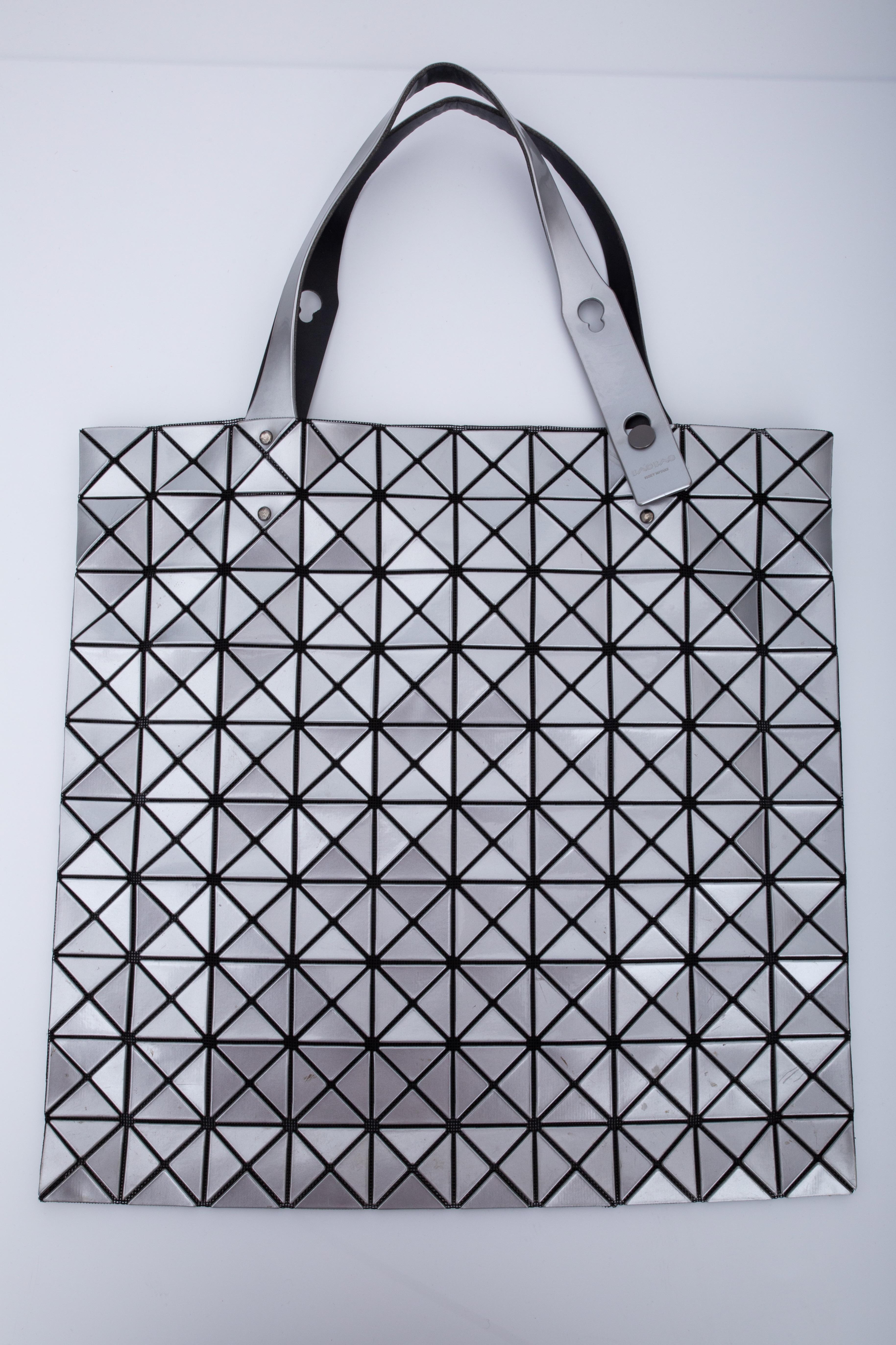 This tote by Issey Miyake is made of black mesh with triangular vinyl appliqués in silver-tone throughout.The bag features an open top with dual cary handle at top.

COLOR: Black mesh with sliver exterior
MATERIAL: Mesh with triangular Vinyl /