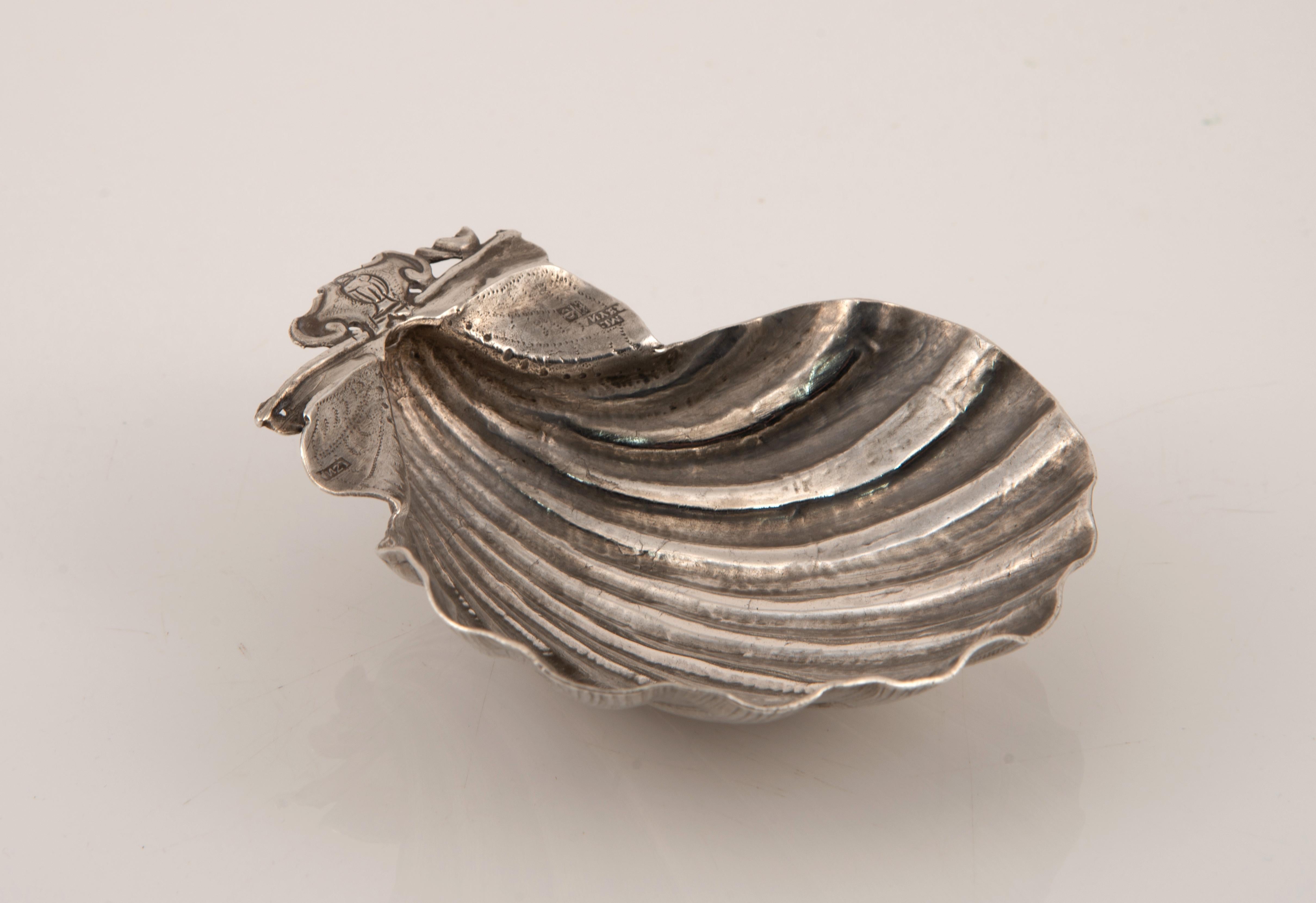 Conchiglia battesimale. Il colore è argento. GARCÍA REINA, Manuel. Toledo, Spagna, 1730-1751 circa. 
Con i segni di contrasto, manca. 
Una conchiglia di colore argento, con dettagli naturalistici, e una parte superiore con un cartiglio (su cui è