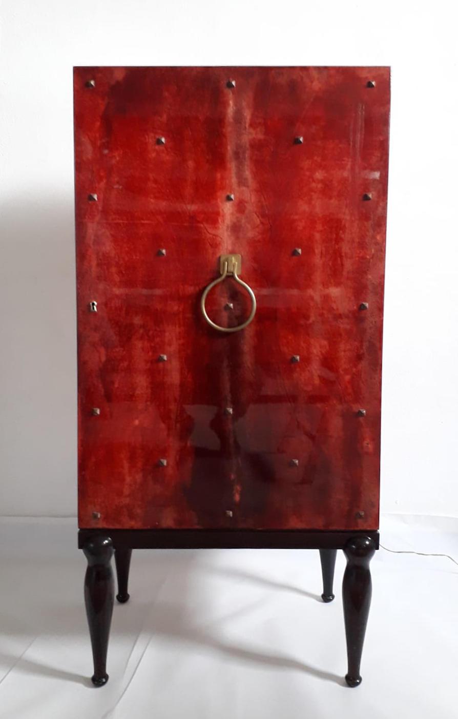 Vintage bar cabinet by Aldo Tura / Made in Italy in the 1960s
Red varnished goatskin parchment, lacquered wood and original brass details.
The interior is mirrored with clear glass shelves and can also be illuminated.
Measures: Height 48.5 inches,