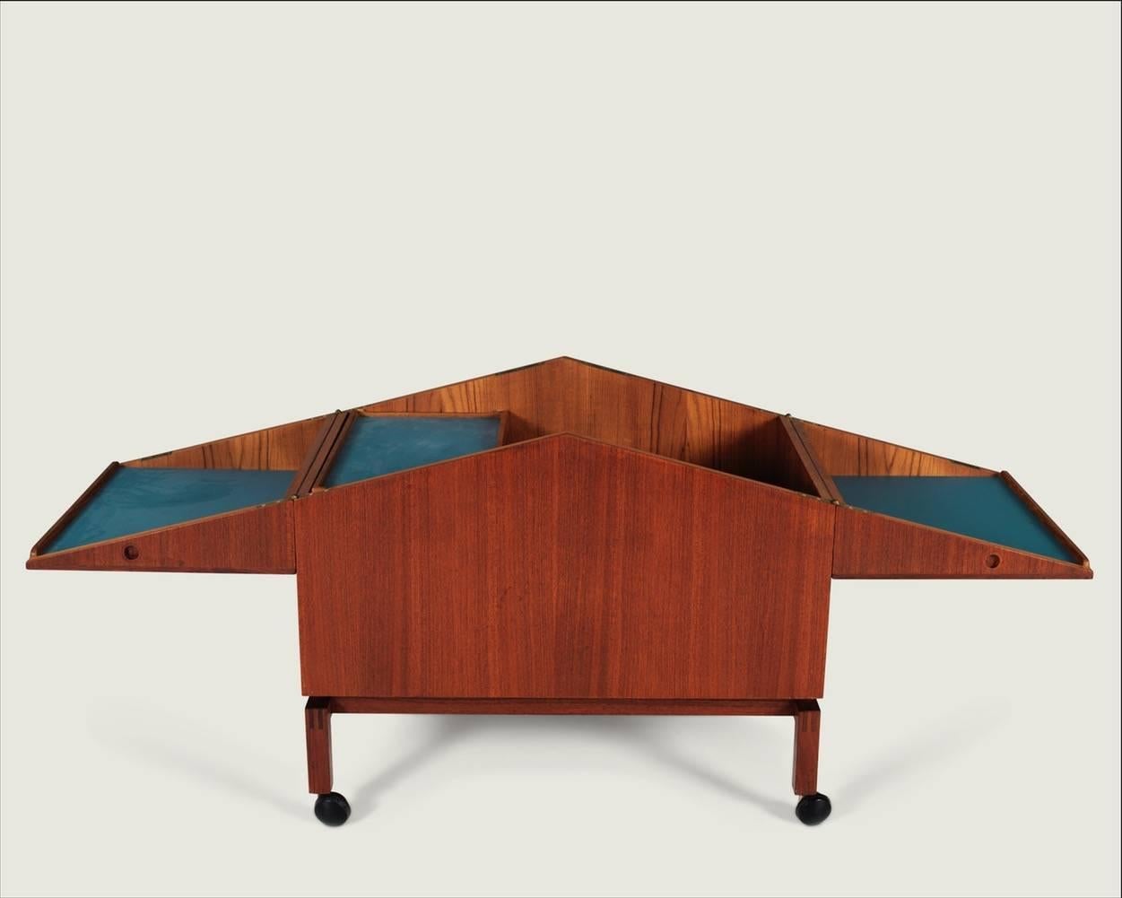 Leif Alring (1936-1987)
Unfolding bar cabinet / model 284 
Teak bar on wheels with blue formica inlay.
Cabinet designed with lockable top, removable tray and compartments for glasses and bottles. Designed in 1964, produced by C. F. Christensen,