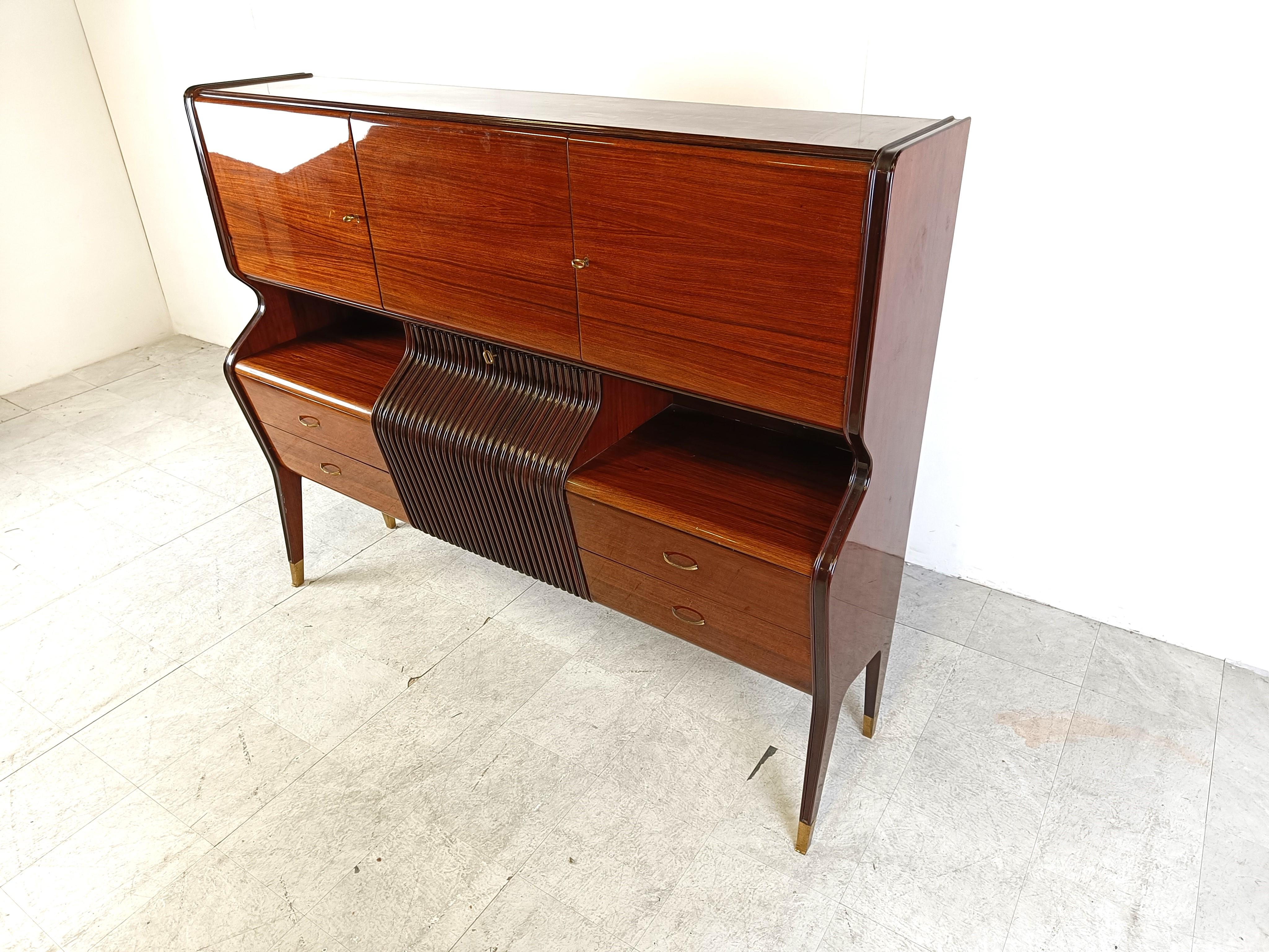 Exquisite bar cabinet designed by Osvaldo Borsani for Atelier Borsani Varedo.

This very elegant mid century italian bar cabinet is made of high quality mahogany wood and has brass tips on the legs

This cabinet consists of 4 drawers, a drop down
