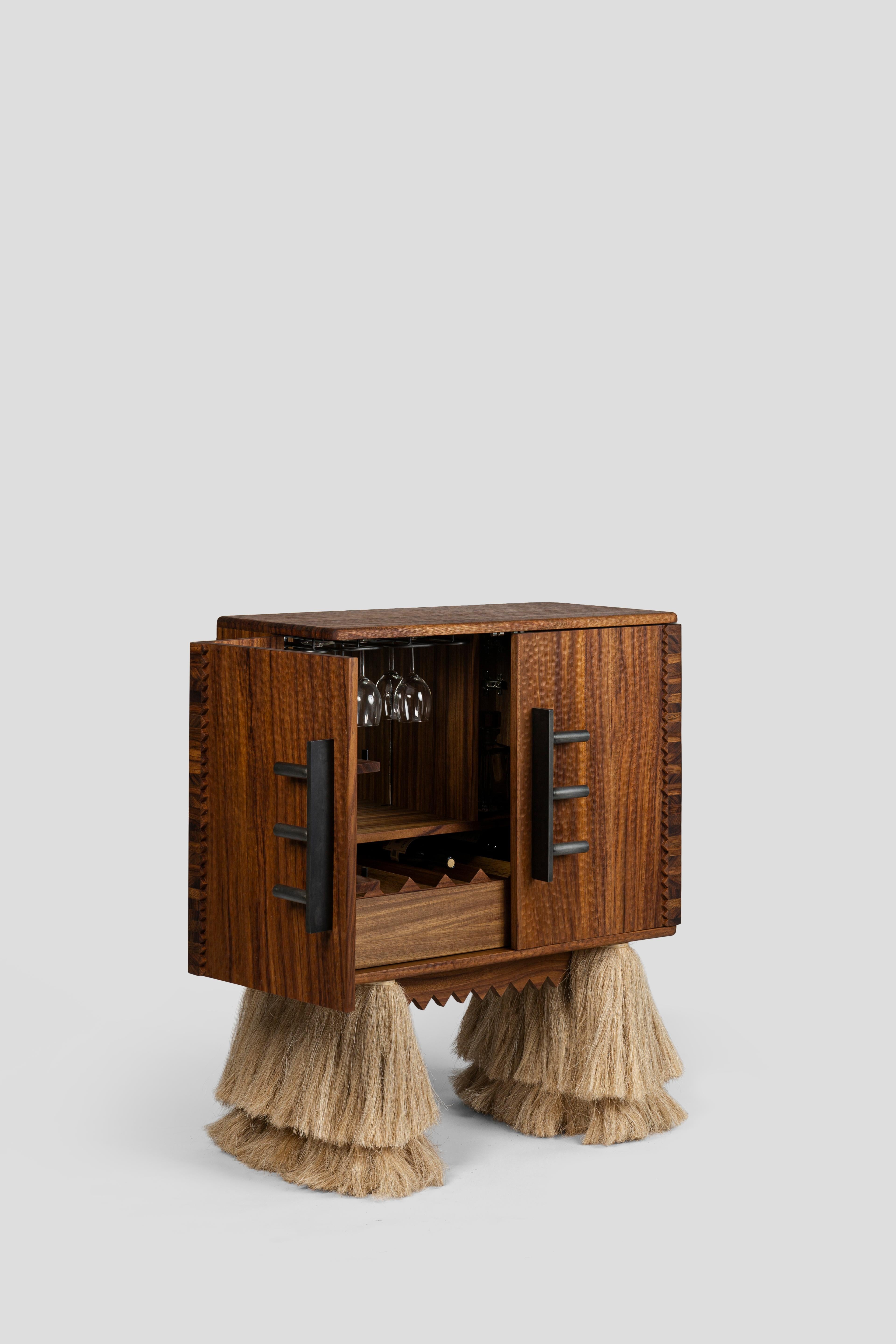 
Carmen is a bartender, a storage cabinet with a functional design. Inside, it has a pair of drawers for storing objects, space for bottles, compartments for glasses and a cup holder. When the doors are opened, the sides of the cabinet reveal
