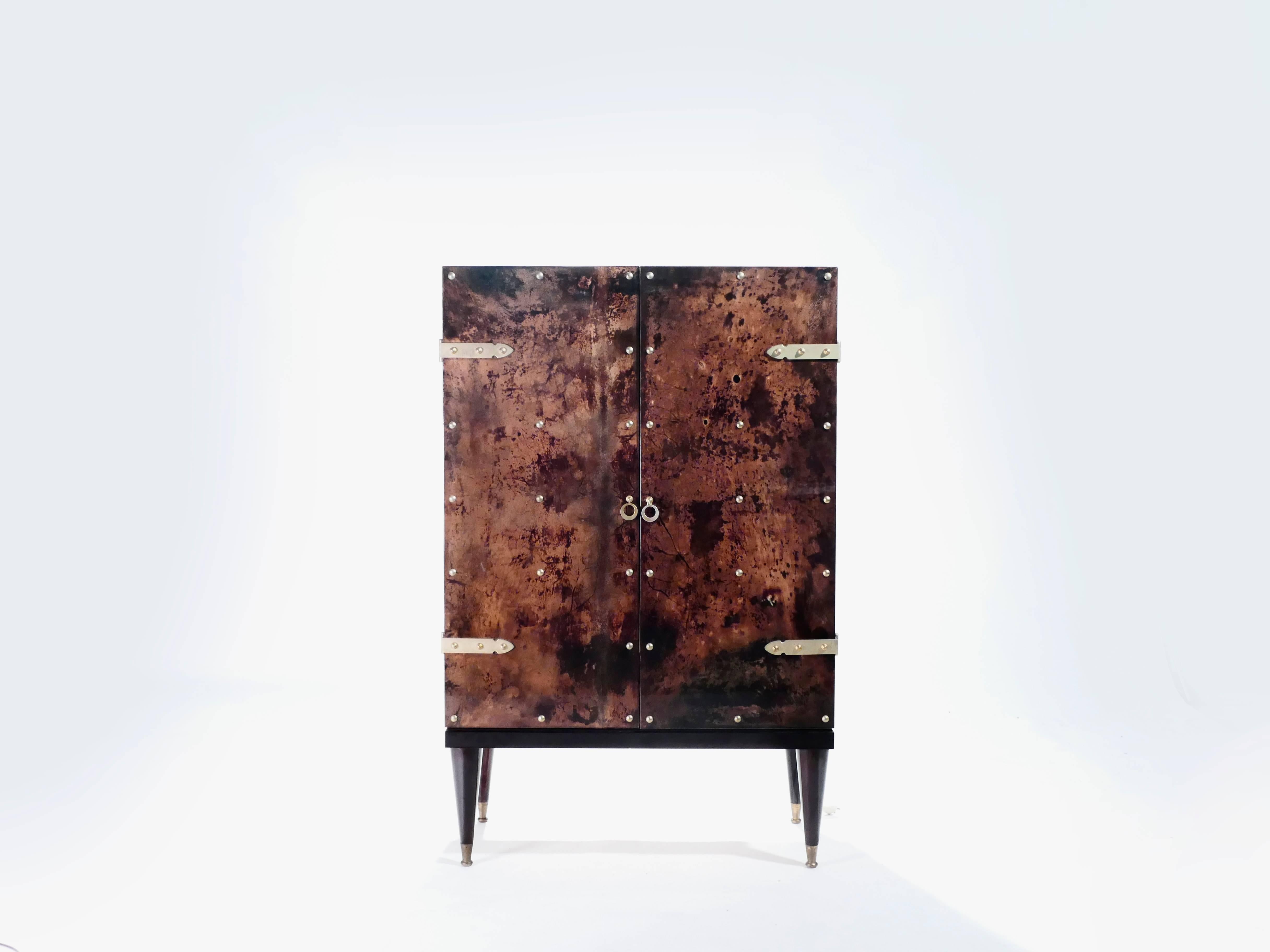 Italian designer Aldo Tura was known for creating decorative pieces that often incorporated goatskin parchment, which creates the lovely dappled, tortoise-shell-like look seen here on this bar cabinet. The varnished goatskin parchment surface, in