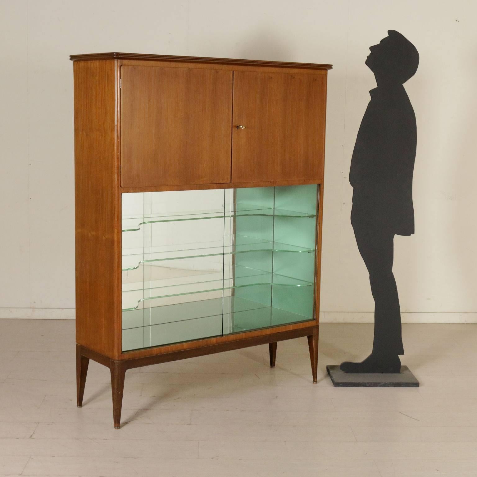 A bar cabinet, sliding glass doors in the lower part and wooden hinged doors in the upper part. Walnut veneer, glass shelves inside and mirrors. Manufactured in Italy, 1950s.