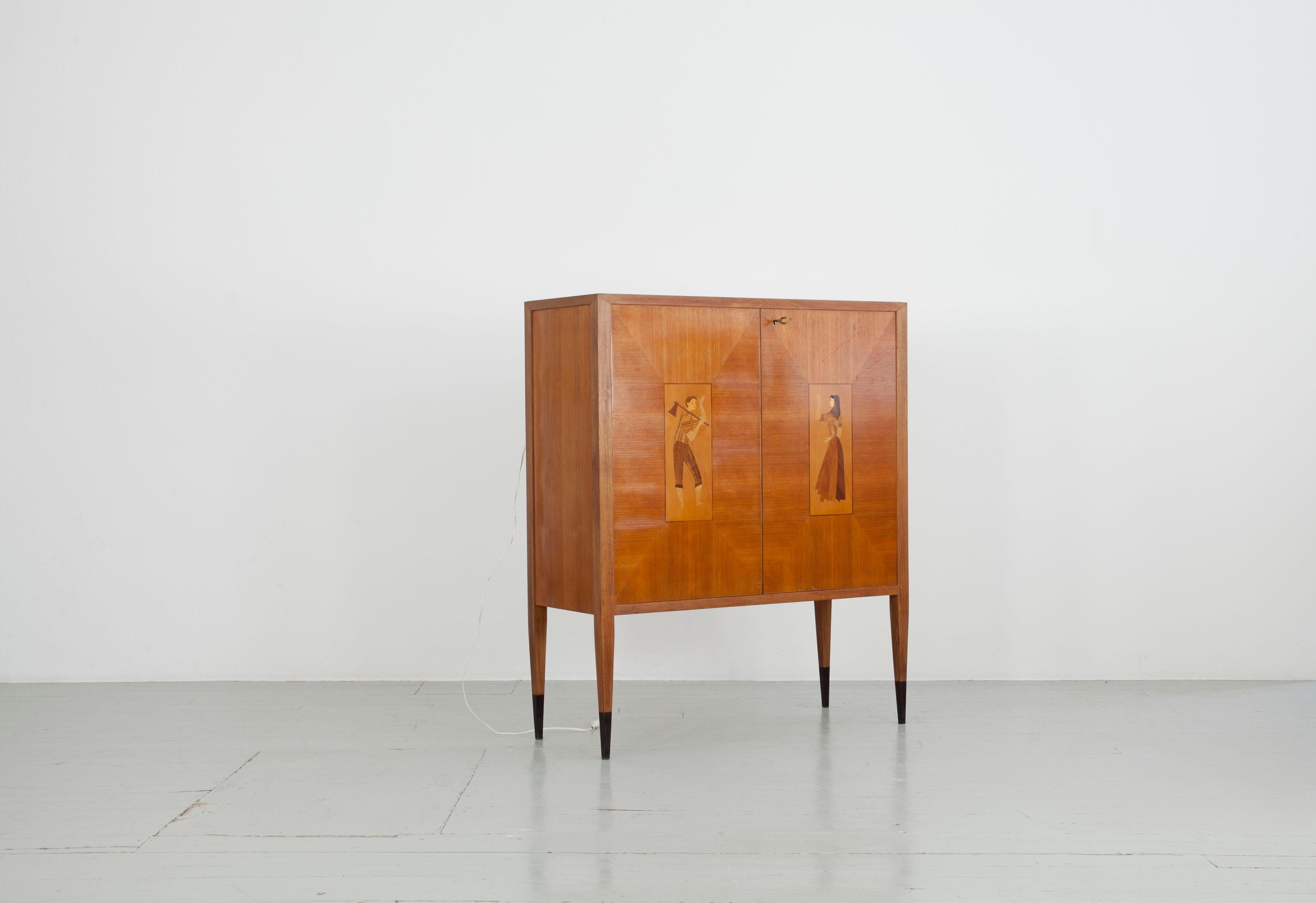 Bar cabinet, Italy, 1950s
Walnut veneer with two inlays of different woods with traditional
figures, inside mirror with lighting. 
Crystal glass with coloured paper applied to the back.