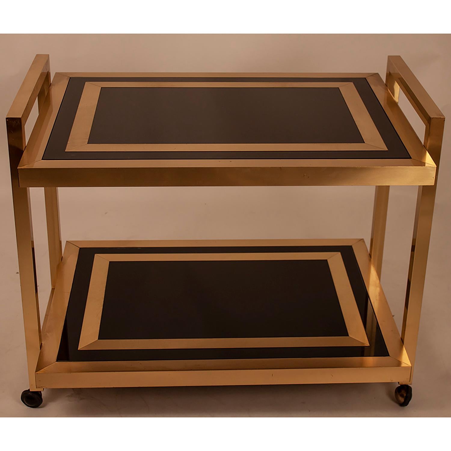 Bar cart, 1970s.
Glass bar trolley in black glass and gold brass. Origin Spanish.
Good quality. Both can be used as a cart or to serve drinks, also as a side table, next to a sofa, is inspired by Willy Rizzo. The contrast of black with gold brass.