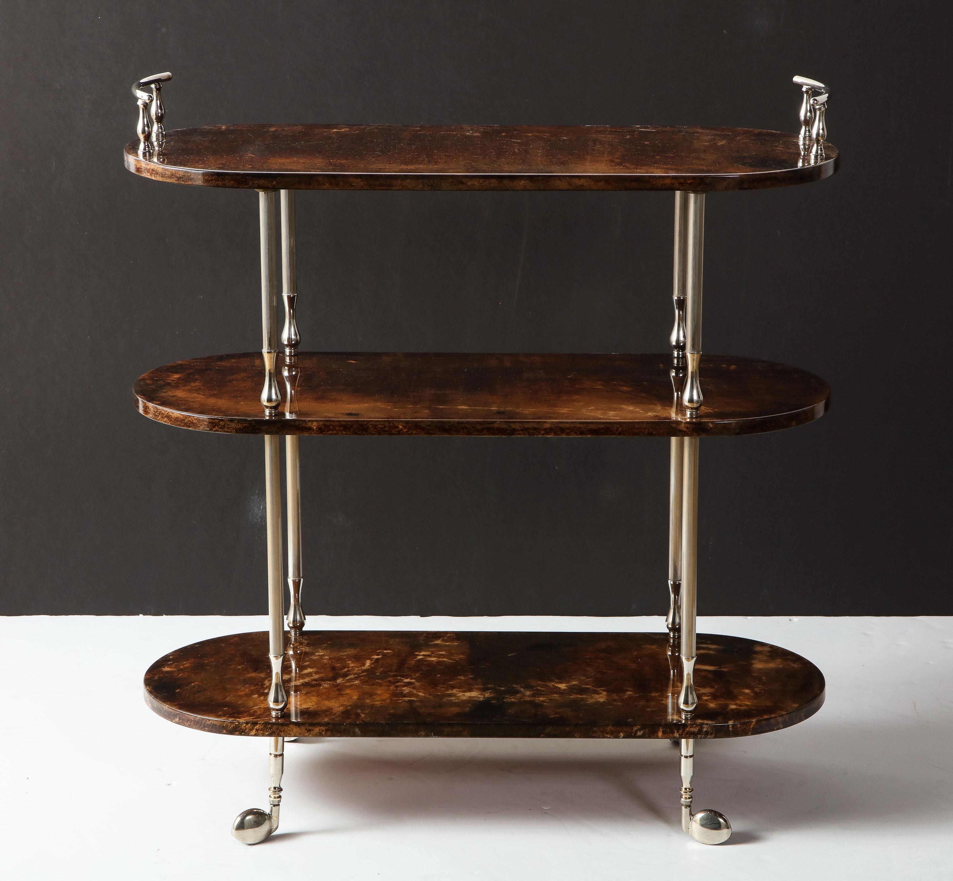 Decorative three shelves bar cart by Aldo Tura, Italy, circa 1950.
Dark chocolate goat skin parchment with polished chrome details.
Between top shelf and middle shelf is 12 inches. Between bottom shelf and middle shelf is 15.75 inches.
The bar