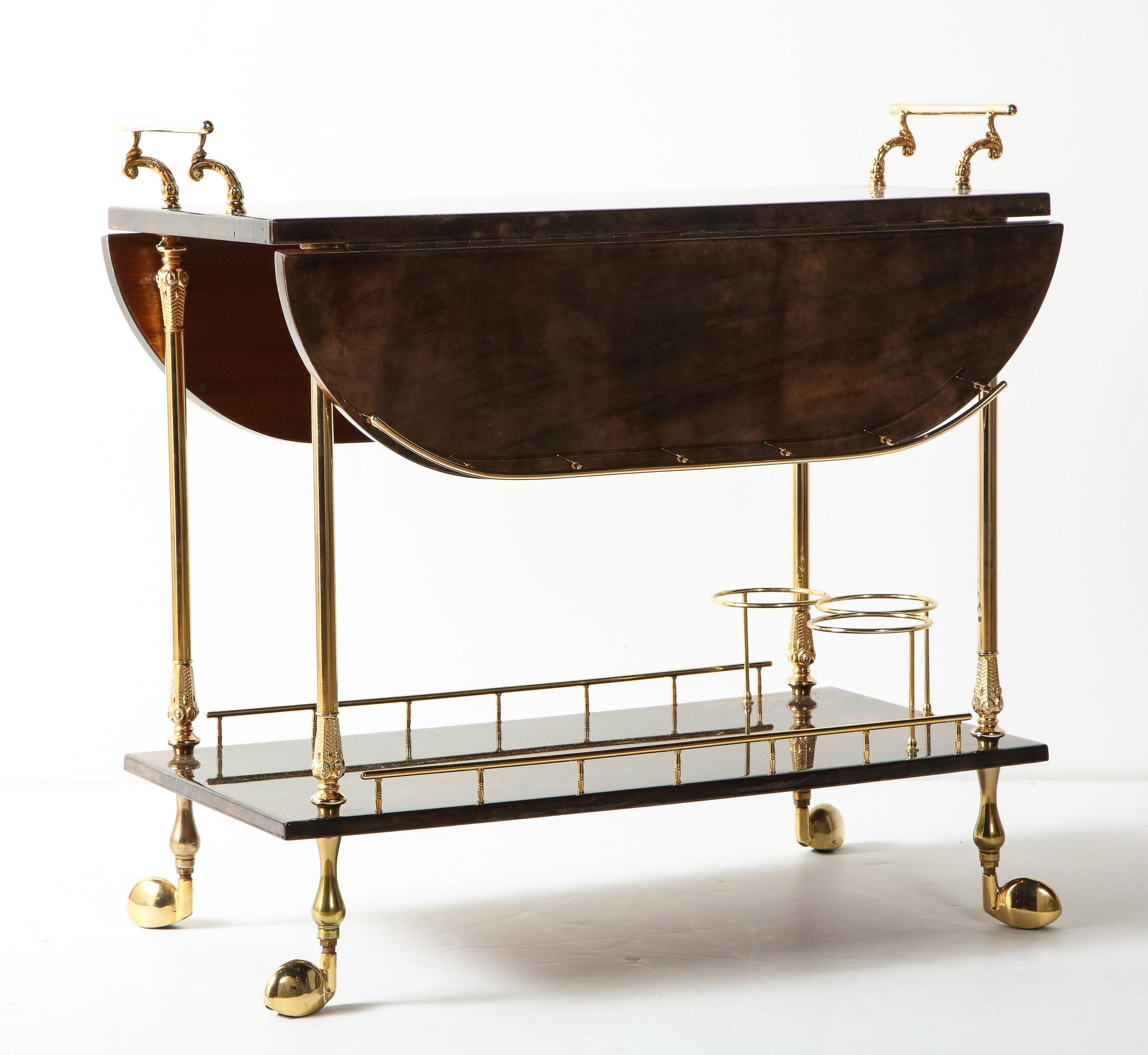 Decorative bar cart by Aldo Tura, Italy, circa 1950. Made of chocolate brown goat skin parchment and polished brass details.
When table is open it measures 30.75 inches. Height including handles is 29 inches. The length of the table without handles