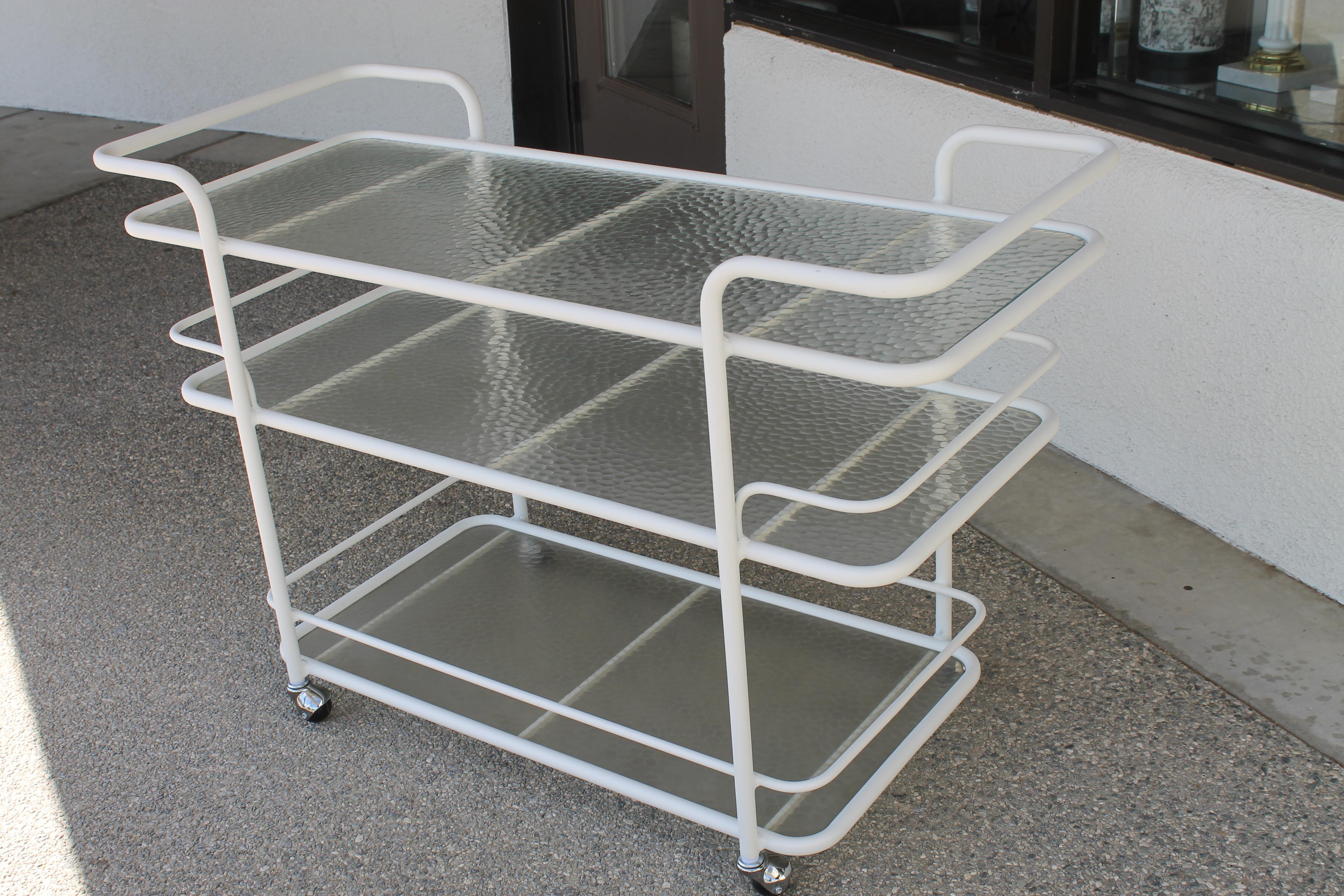 Three-tier aluminum bar cart designed by Richard Frinier for Brown Jordan. Reminiscent of Walter Lamb designs. Contains original glass. We replaced steel rollers. This bar cart has been sand blasted and powder-coated a white satin. Cart measures: