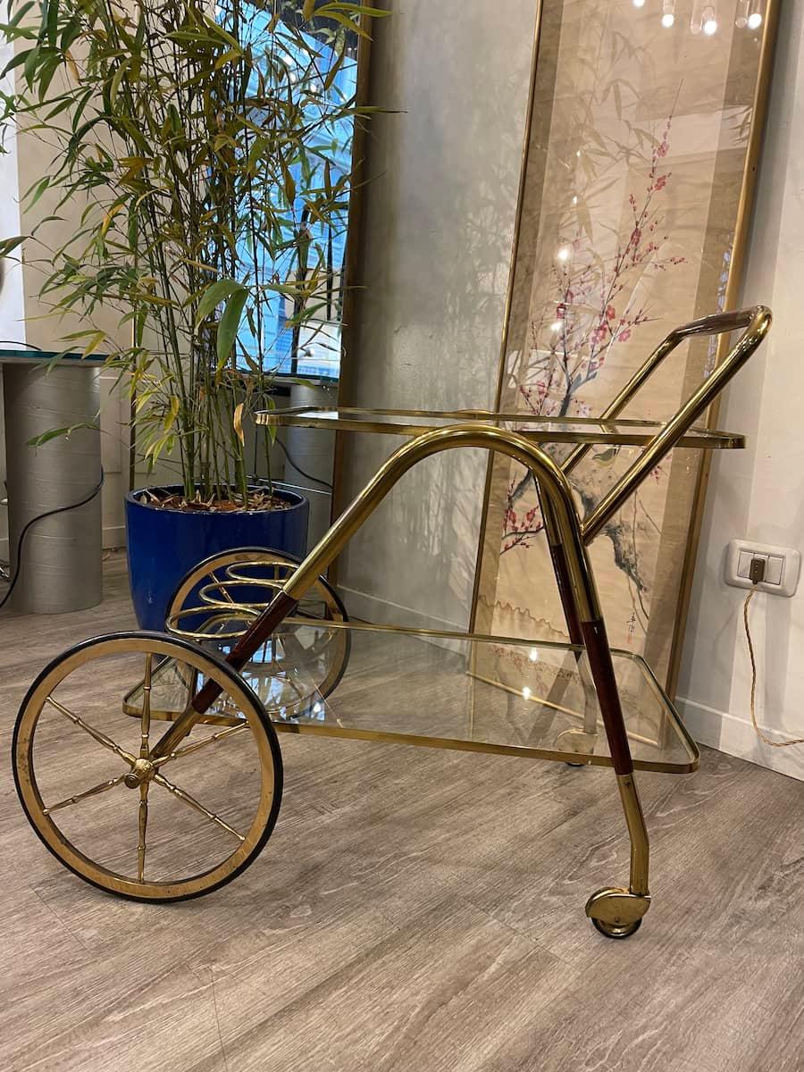 Bar cart with double shelf and bottle holder space in Cesare Lacca style. Some details of the trolley are in ebony-stained wood, the structure is brass, and the shelves are glass. 

Measurements are: 85 x 45 x H 73cm.

Price INCLUDES the costs for