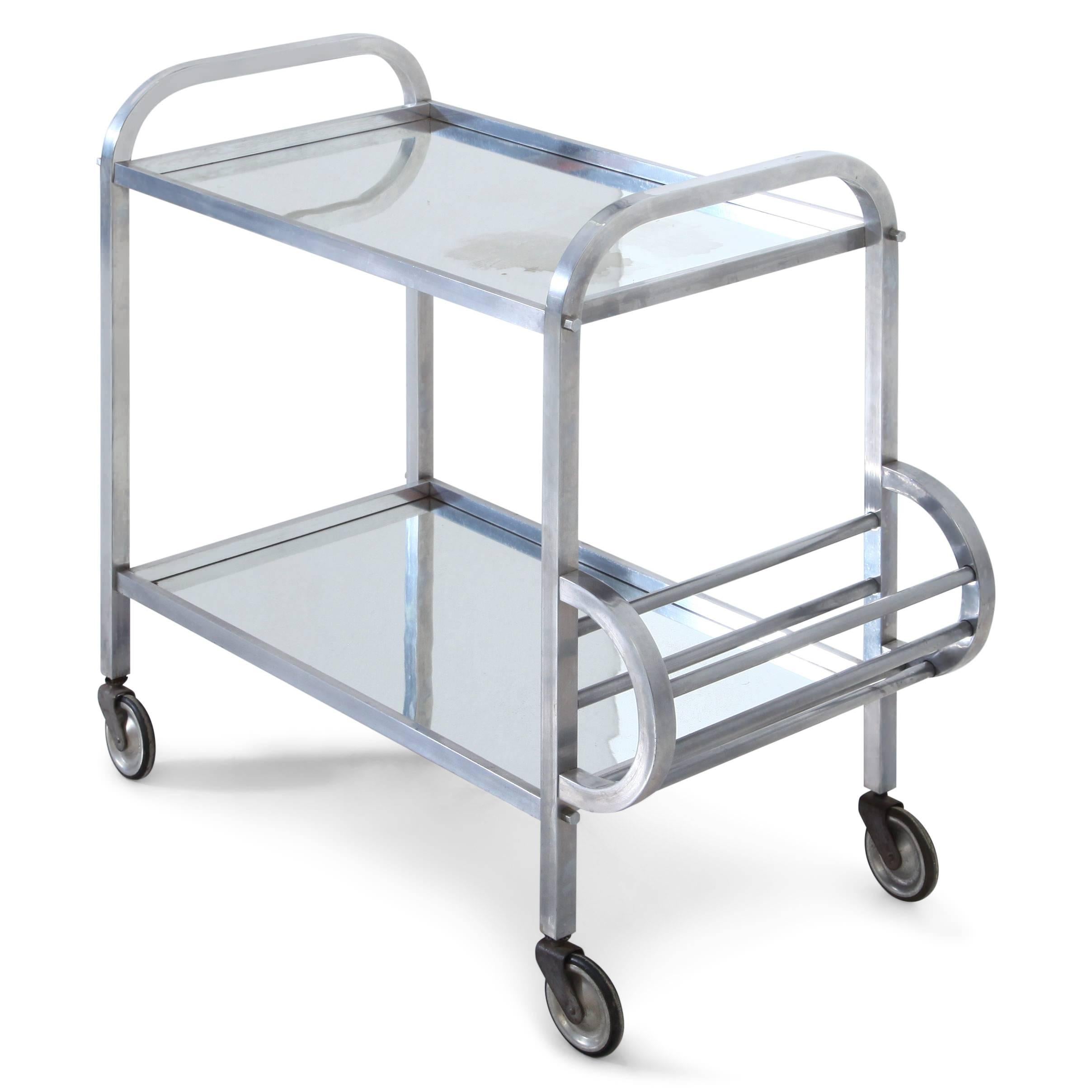 Serving trolley or Bart cart out of aluminium in the style of Jacques Adnet. The trolley stands on four wheels and has two tiers with a bottle holder on one side.