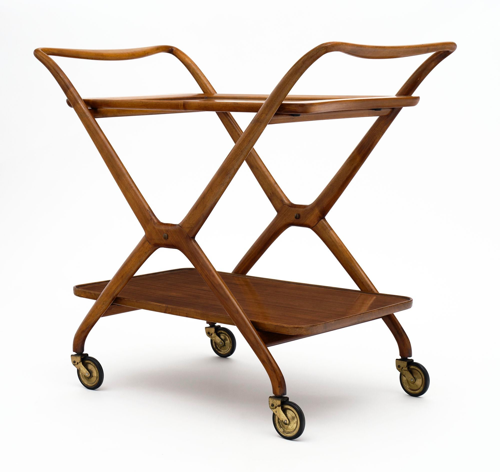 The tea trolley model 67 is characterized by a structure formed by the union of two X-shaped supporting elements, in solid wood, joined at the top by shaped handlebars; opposed and stiffened by crosspieces placed under the two support surfaces. The