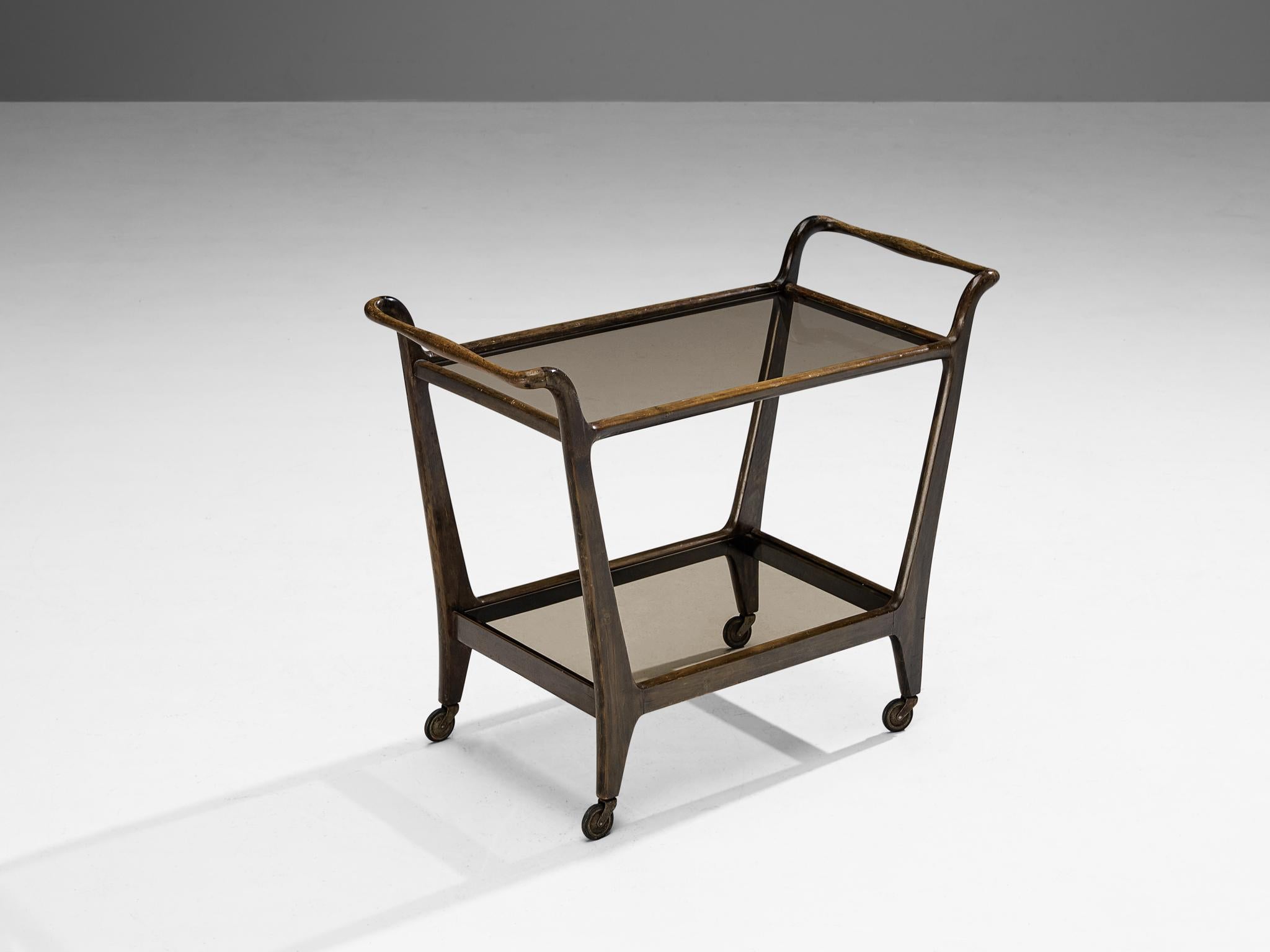 Bar cart or tea trolley, wood, glass, metal, Europe

Bar cart or serving trolley made in wood and displaying two smoked glass levels. This cart is made in the 1950s and shows delicate traits. The small and elegant wheels, the tapered handlebars