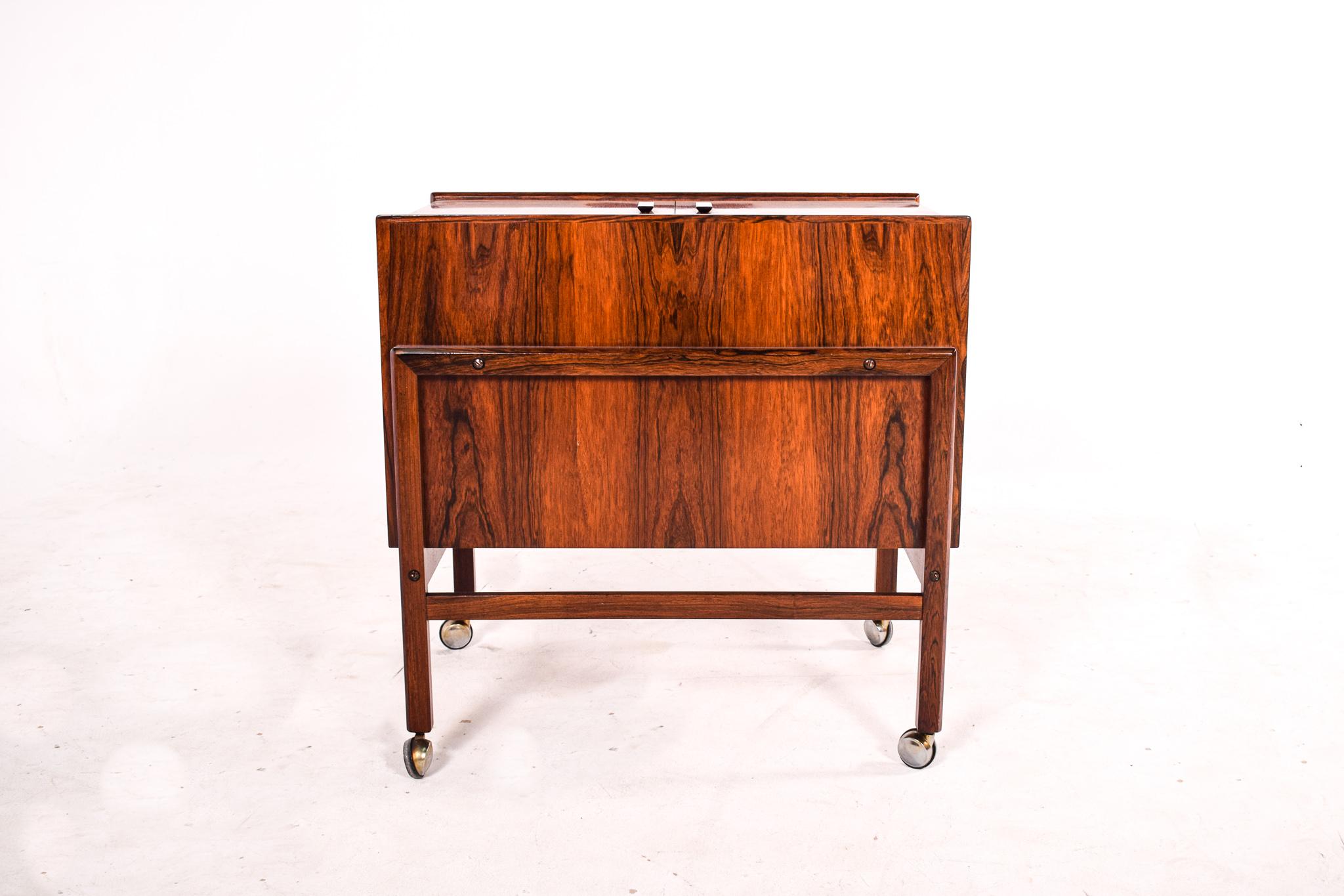 Danish design at its best. Bar cart in rosewood by Andreas Hansen for Arrebo Mobler in the 1960’s. The top opens out to reveal a fantastic bar space, complete with serving shelves and a bottle rack. Supported on casters for easier movement.