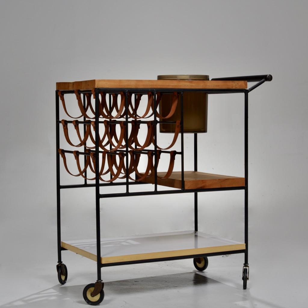 Bar cart or serving cart with wine rack and wooden butcher block top designed by Arthur Umanoff.
This bar cart features leather straps to carry nine wine bottles, a removable ice bucket, and a thick butcher block top. The cart is on original