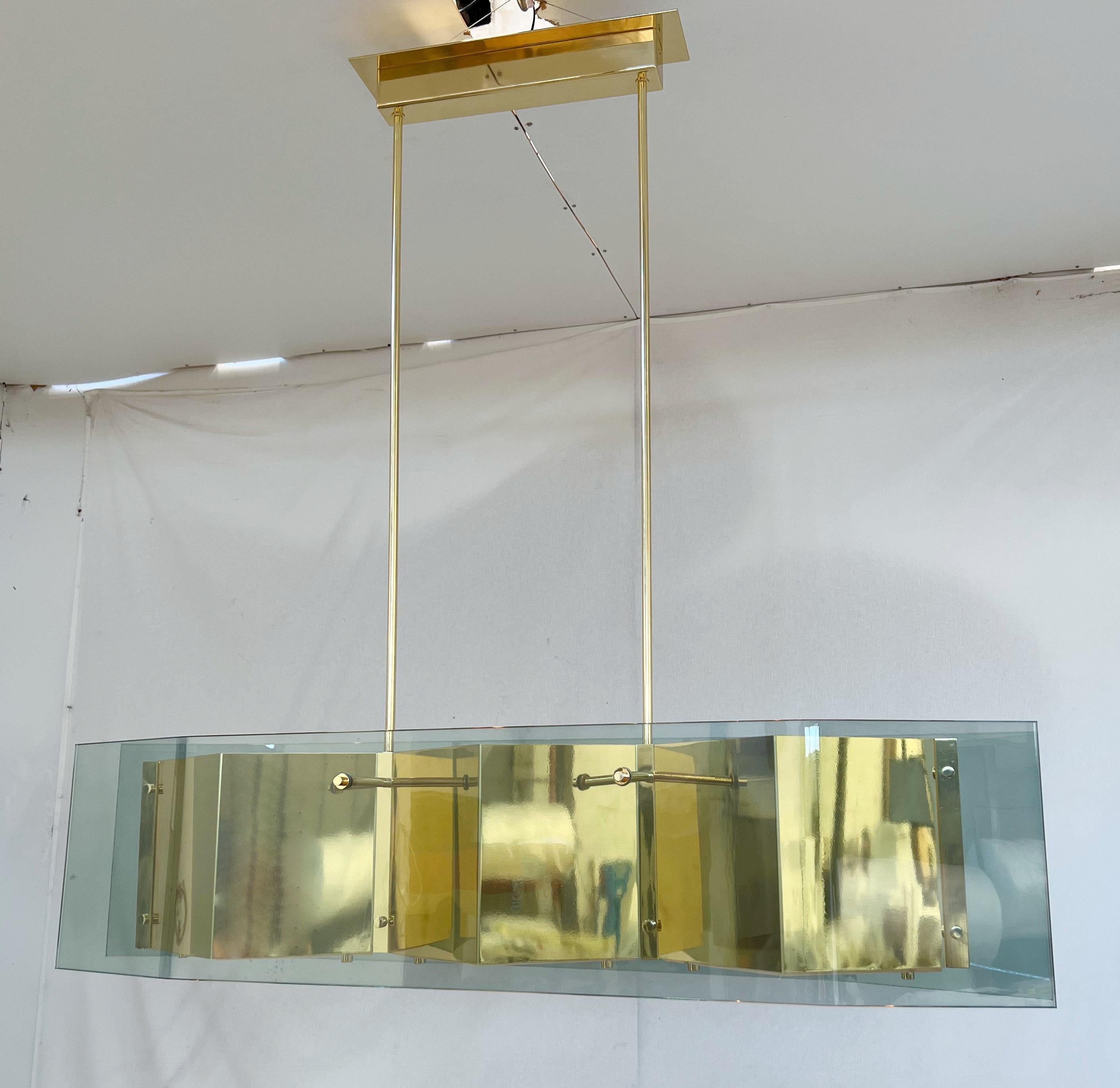 Italian modern chandelier with elongated light green glass panels mounted on polished brass frame with diamond shaped bottom glass diffusers / Made in Italy.
Measures: width 52.5 inches / depth 10.5 inches / height 12.5 inches / total height 51