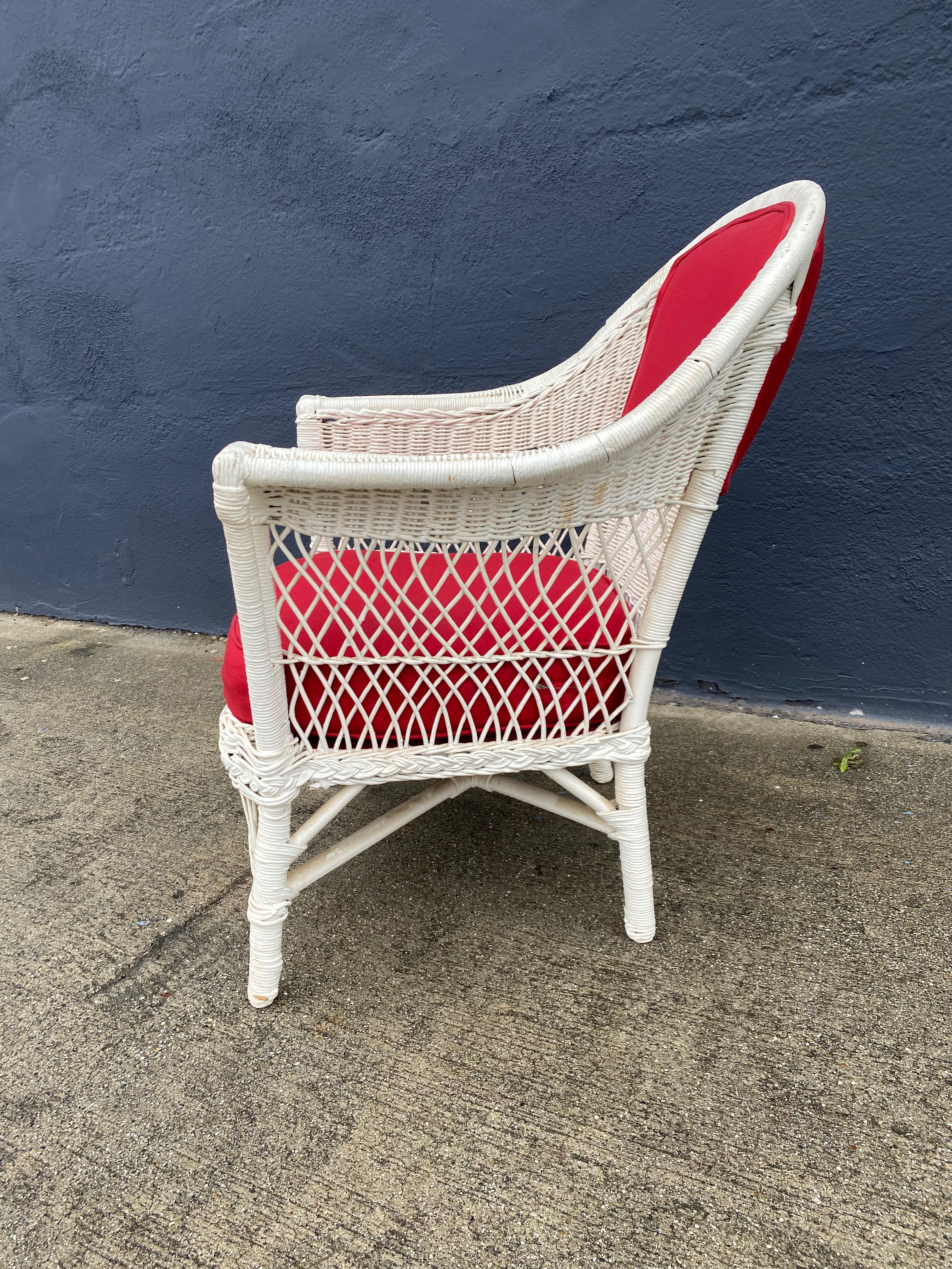 Il s'agit d'une chaise classique en osier de style Bar Harbor datant de la première moitié du XXe siècle. La chaise a été retapissée dans un tissu rouge cerise et repeinte à la fin du XXe siècle. La chaise est en très bon état ; la tapisserie, bien