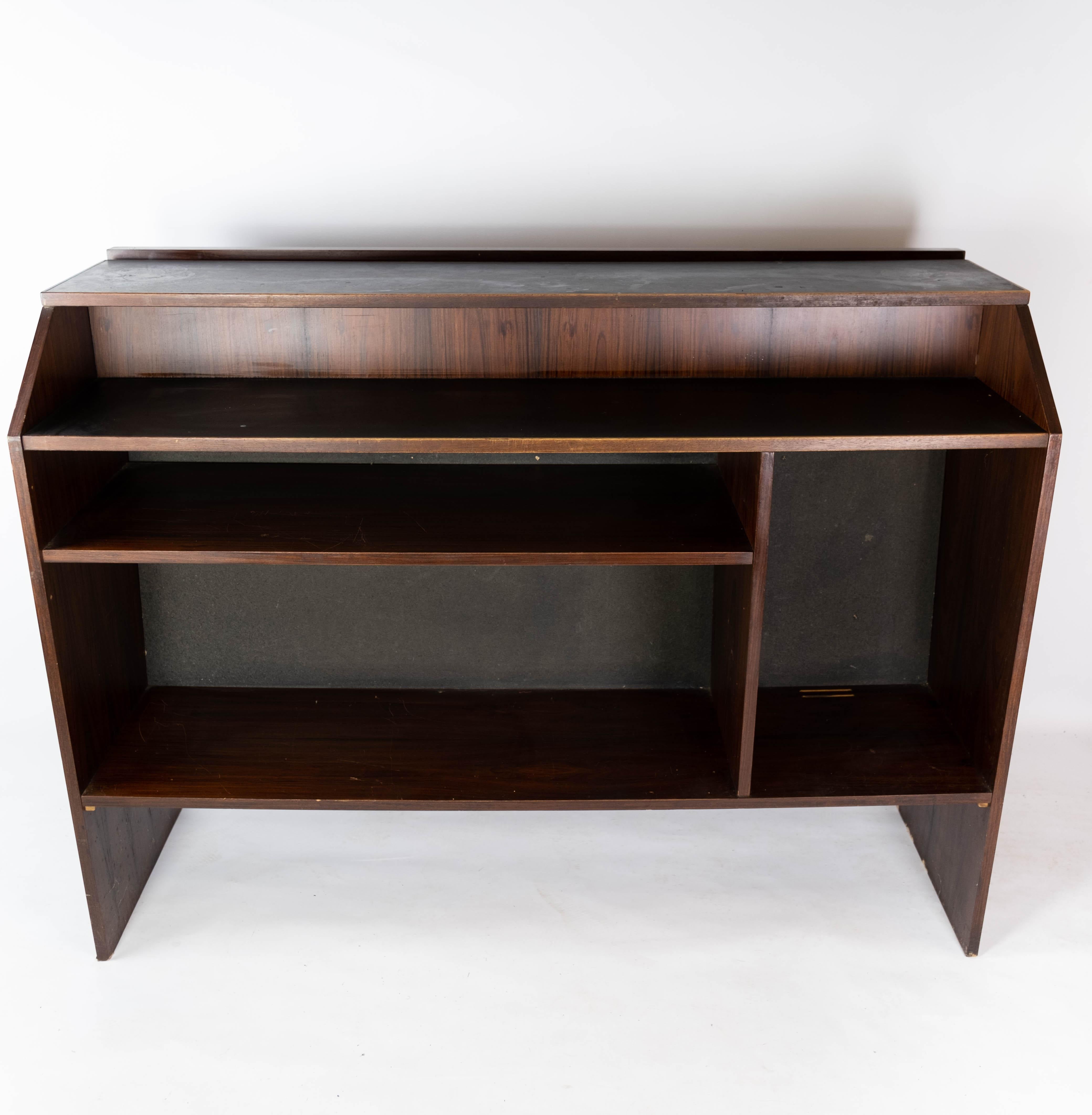 The rosewood bar, crafted in the 1960s with Danish design sensibilities, epitomizes the elegance and craftsmanship of Scandinavian Modern furniture. Its sleek lines and rich rosewood finish make it a timeless piece that adds sophistication to any