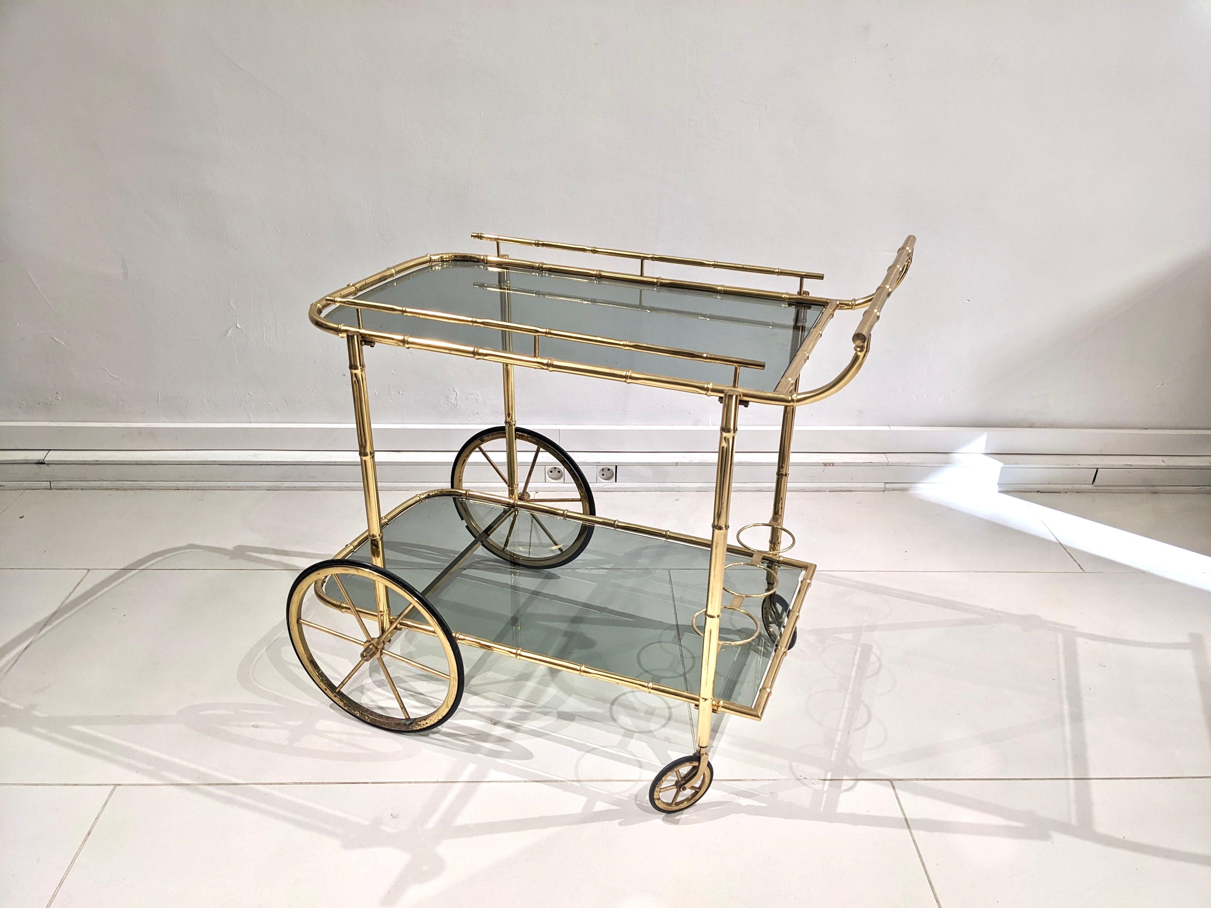 Good condition. Circa 1960. Structure in the shape of gilded bamboo. The two trays are in tinted glass. 
Dimensions : H 78,5 cm x D 44 cm x W 80 cm.