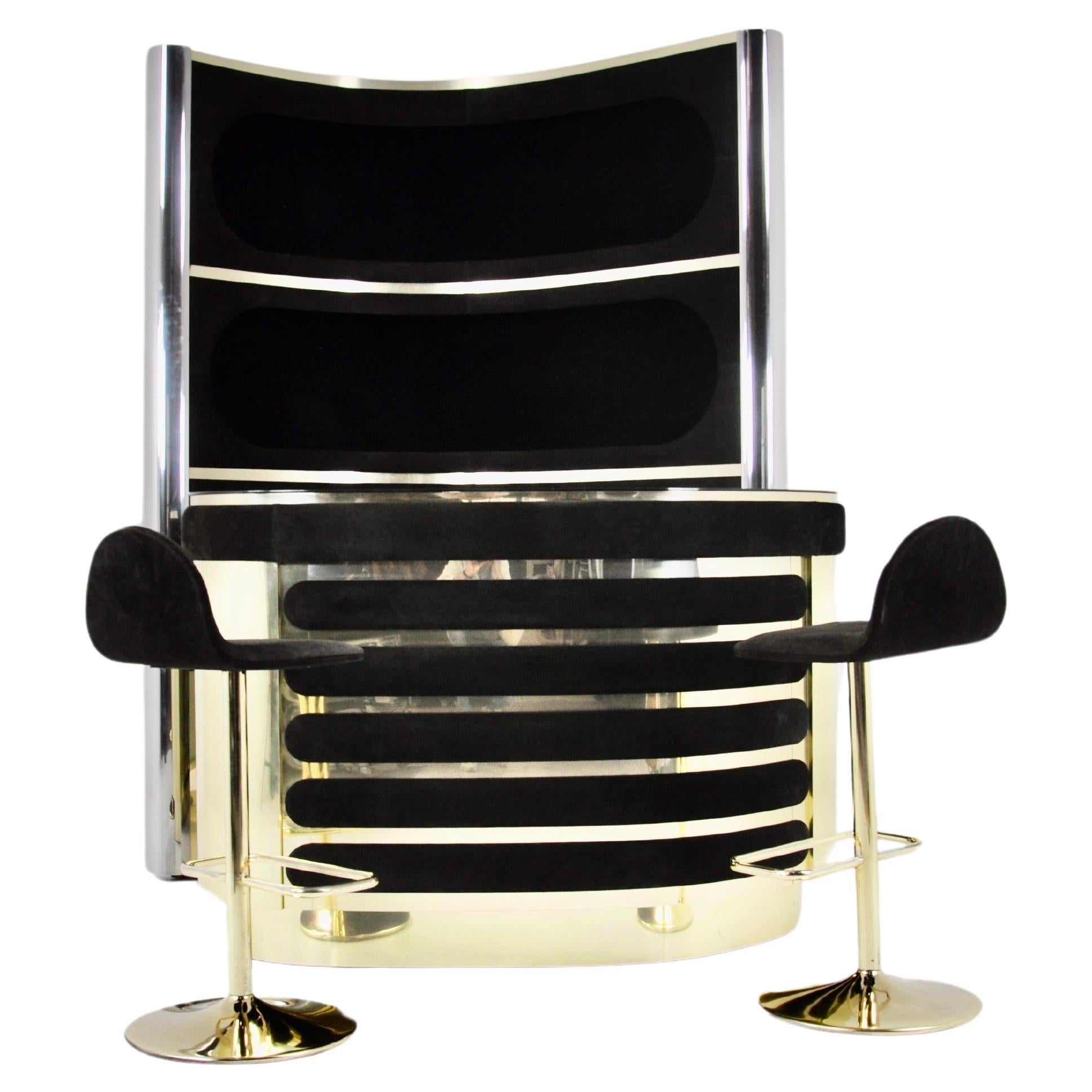 The set includes a cabinet with 3 illuminated shelves in black suede, chromed metal and brass, one of the sides at the back is mirrored glass.  It also includes a suede and brass countertop with a mirrored top, a refrigerator and a glass cabinet