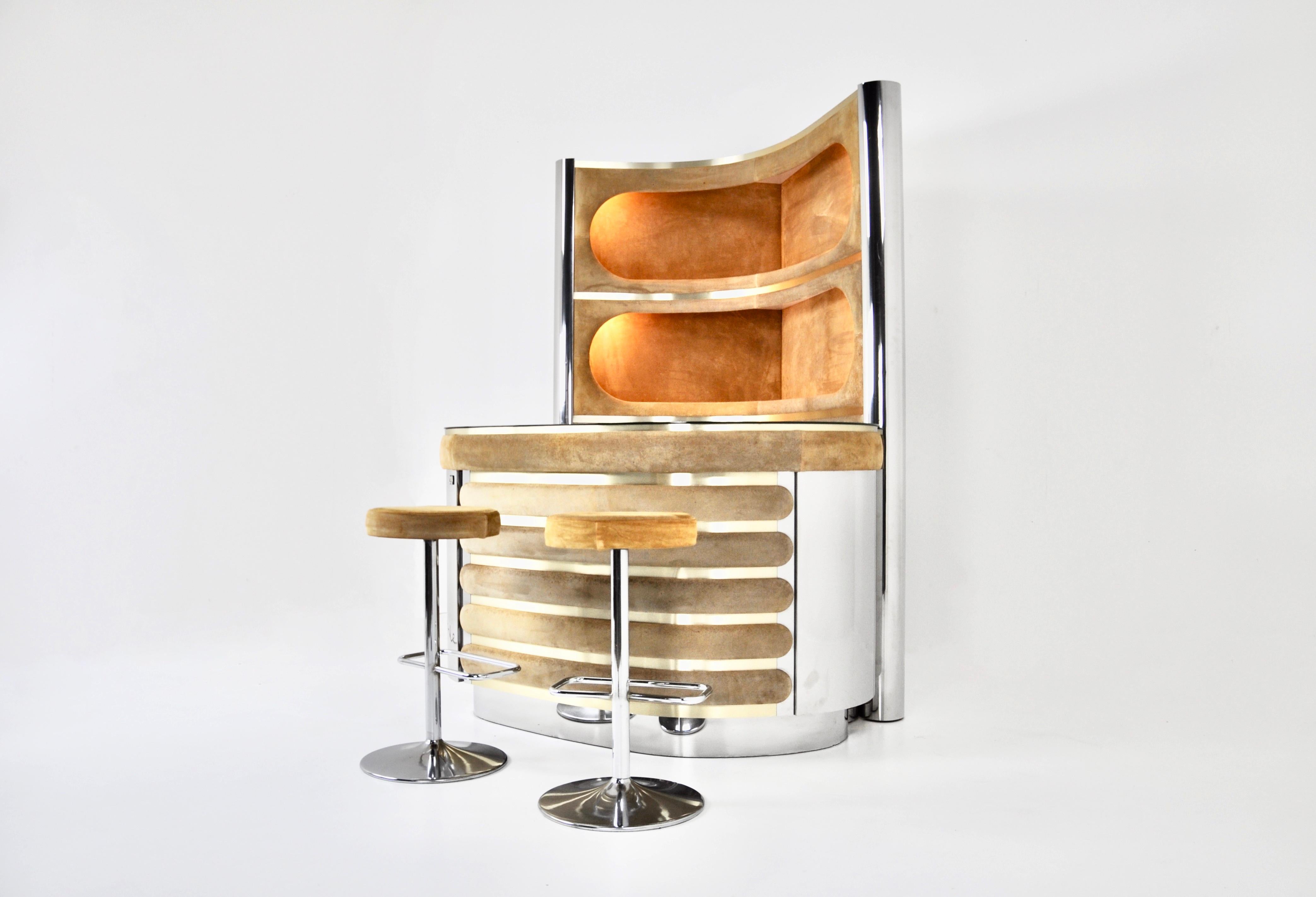 El conjunto incluye un mueble con 3 estantes iluminados de ante, metal cromado y latón.  También incluye un mostrador de ante, metal cromado con tapa de espejo, un frigorífico y una vitrina con estante. El suelo es de moqueta. 
Dimensiones de los