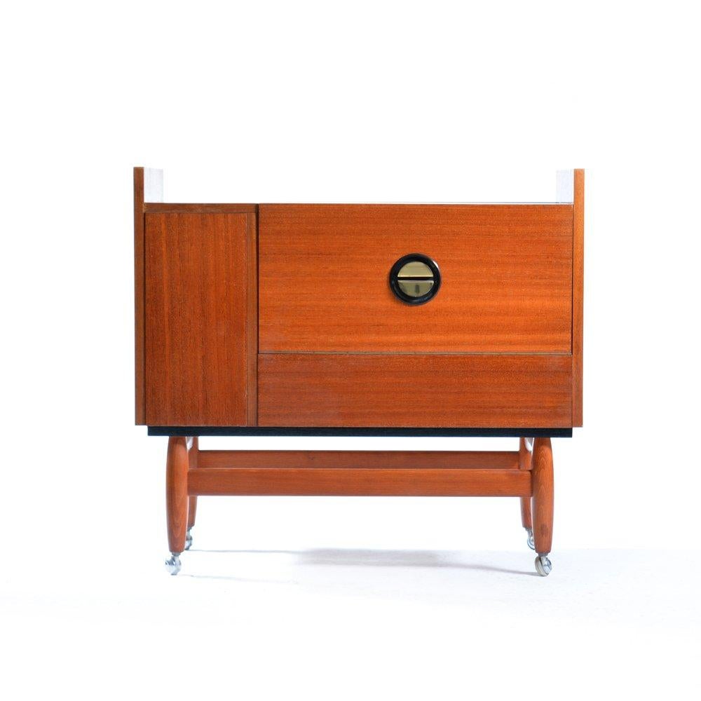 Beautiful midcentury modern bar sideboard standing on  brass wheels. The bar is in magahony wood with high sheen finish. The handles are original and have an interesting round shape. They are also made of brass. The bar is easy to open from both