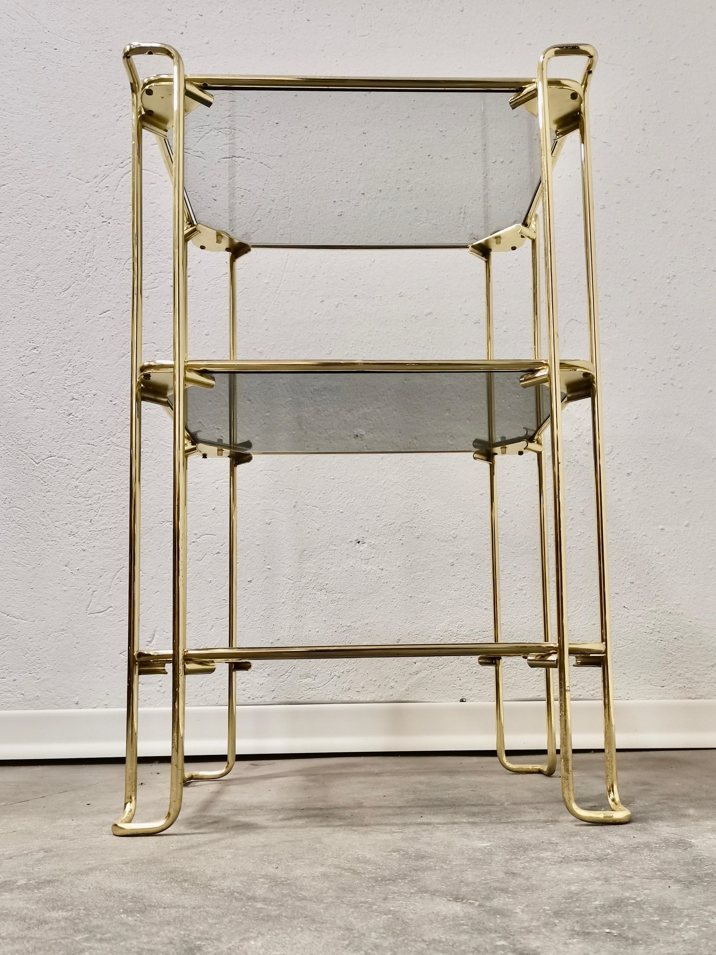 Magnificent Italian brass vintage bar stand. All original parts. The side table has three shelves in smoked glass. Its modern yet classic design gives impression of luxury and style. It can be combined with all styles of furniture and