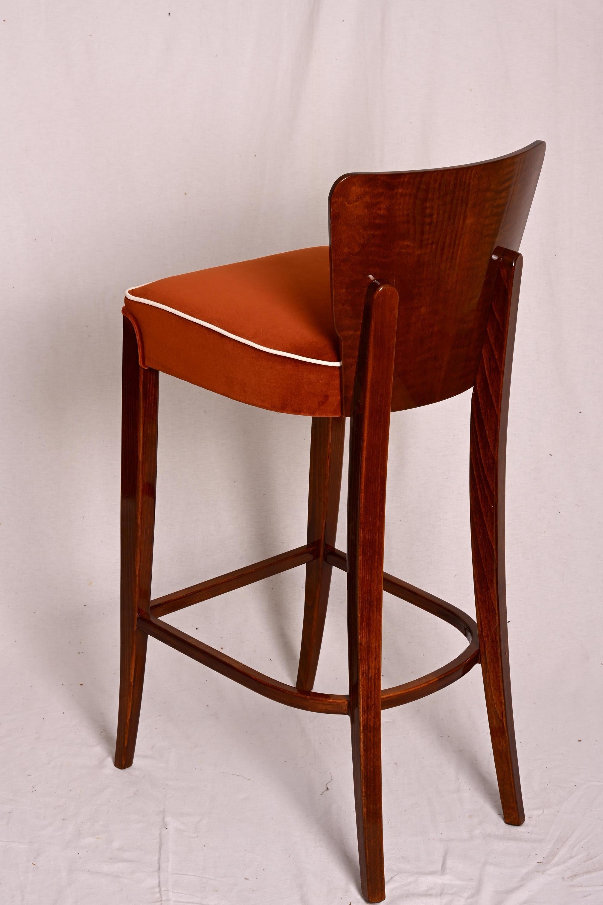Taburetes de bar con respaldo de nogal y patas de haya teñida de color nogal. Asiento tapizado.