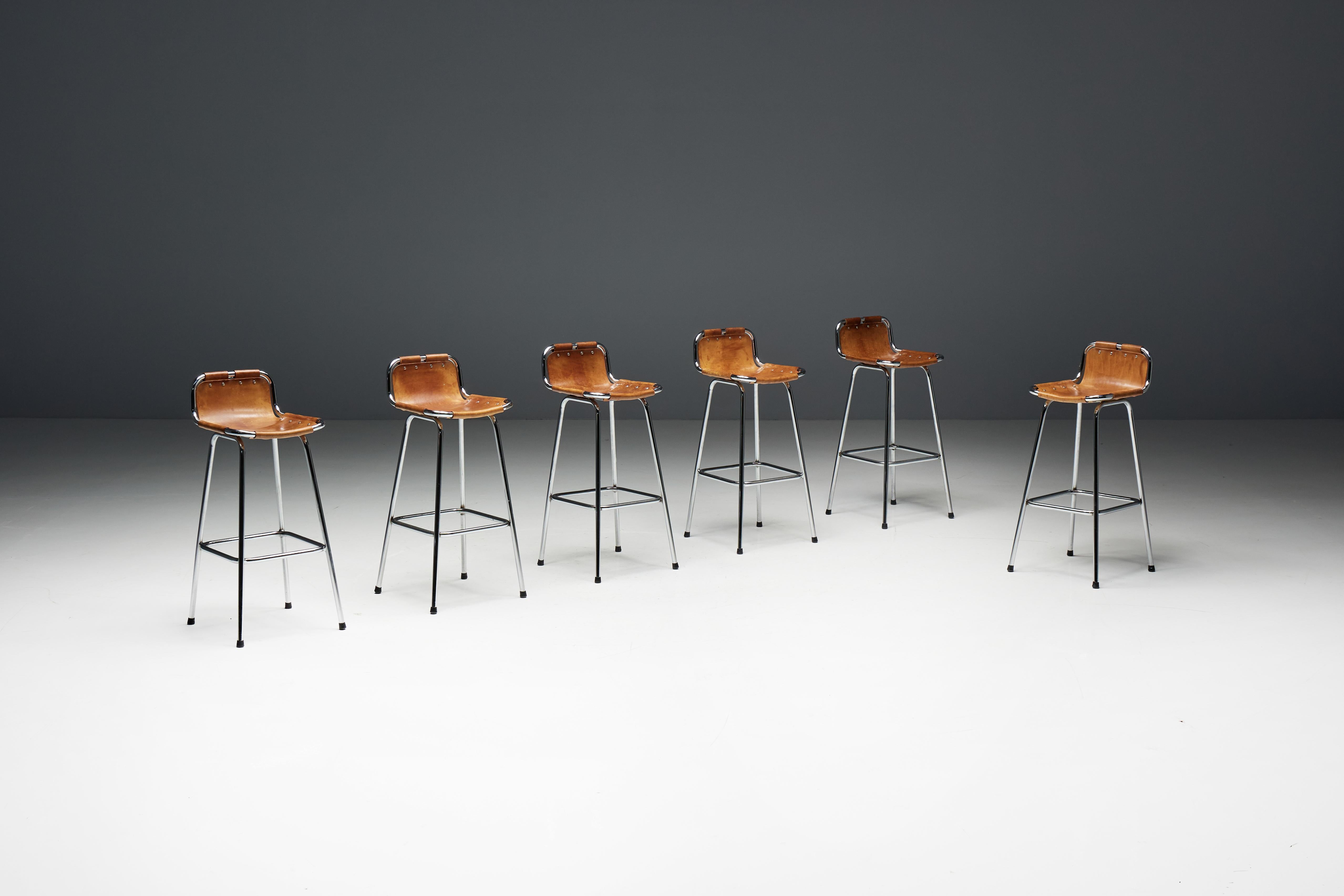 Bar stools designed by Charlotte Perriand for the renowned Les Arcs Ski Resort in France during the 1960s. Each stool features a chrome-plated tubular metal frame and seats crafted from rich cognac leather, which has aged beautifully over the years
