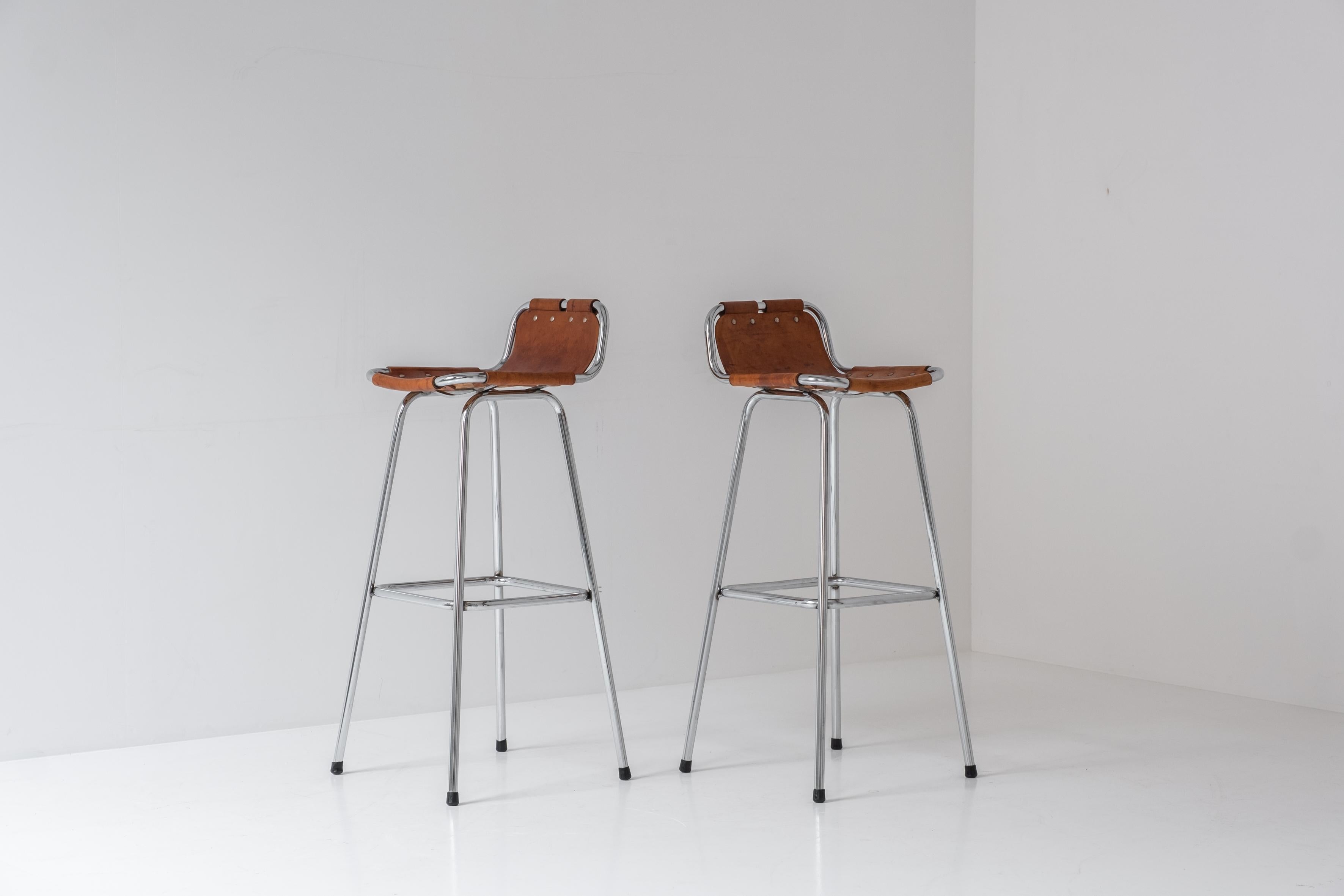 Set of two bar stools selected by Charlotte Perriand for the famous Ski Resort Les Arcs, France 1960’s. These stools features chrome frames and cognac leather seats. Nice overall patina !