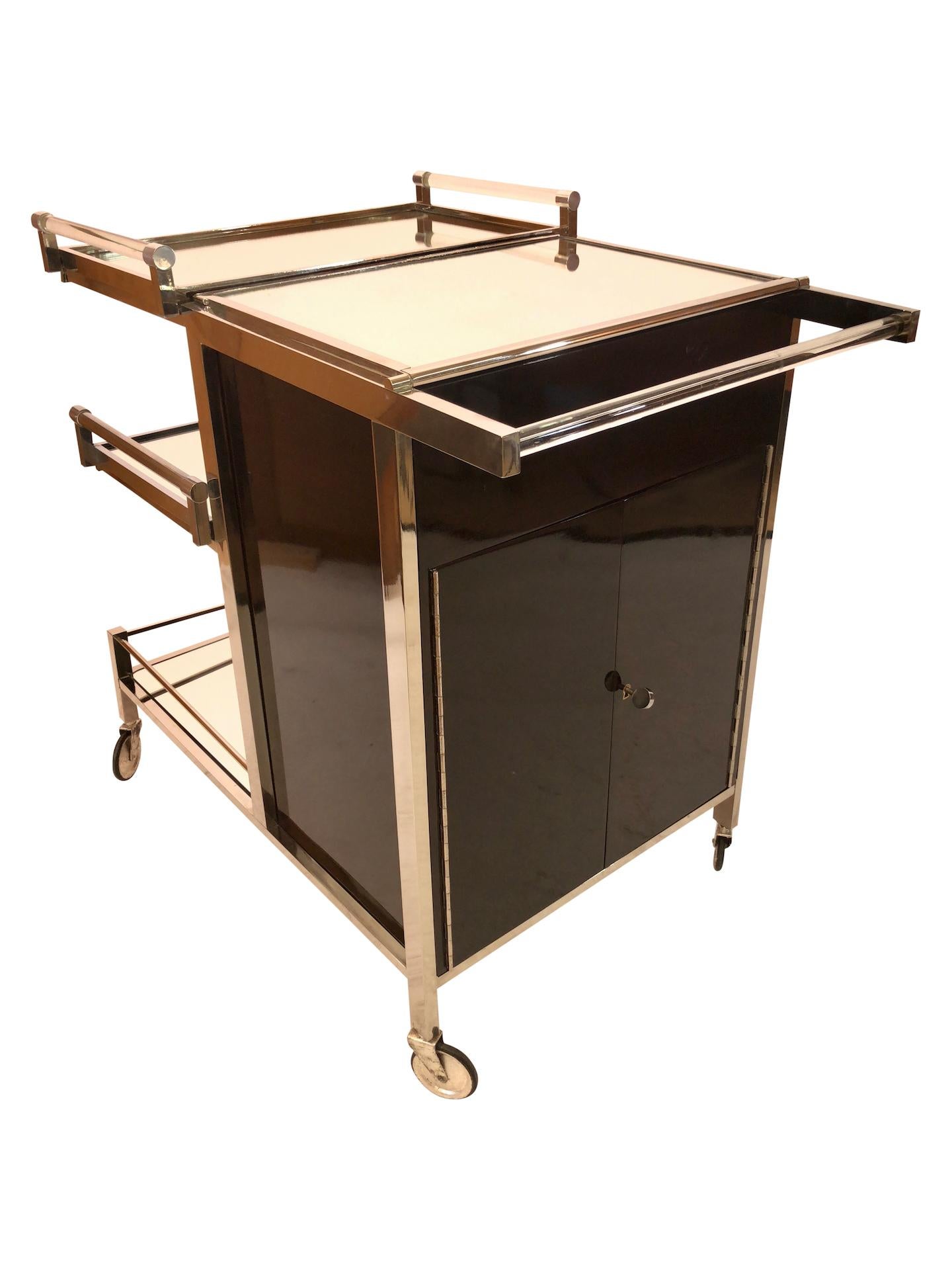 Art Deco bar cart or tea wagon
Original Jacques Adnet 
2 removable trays 
French Art Deco, 1930s 

Pictures take in a warm lighted ambience. 
Metal: brass is fresh nickeled or chromed! 
Real wood veneer (Mahagoni) 
Some mirrors has been
