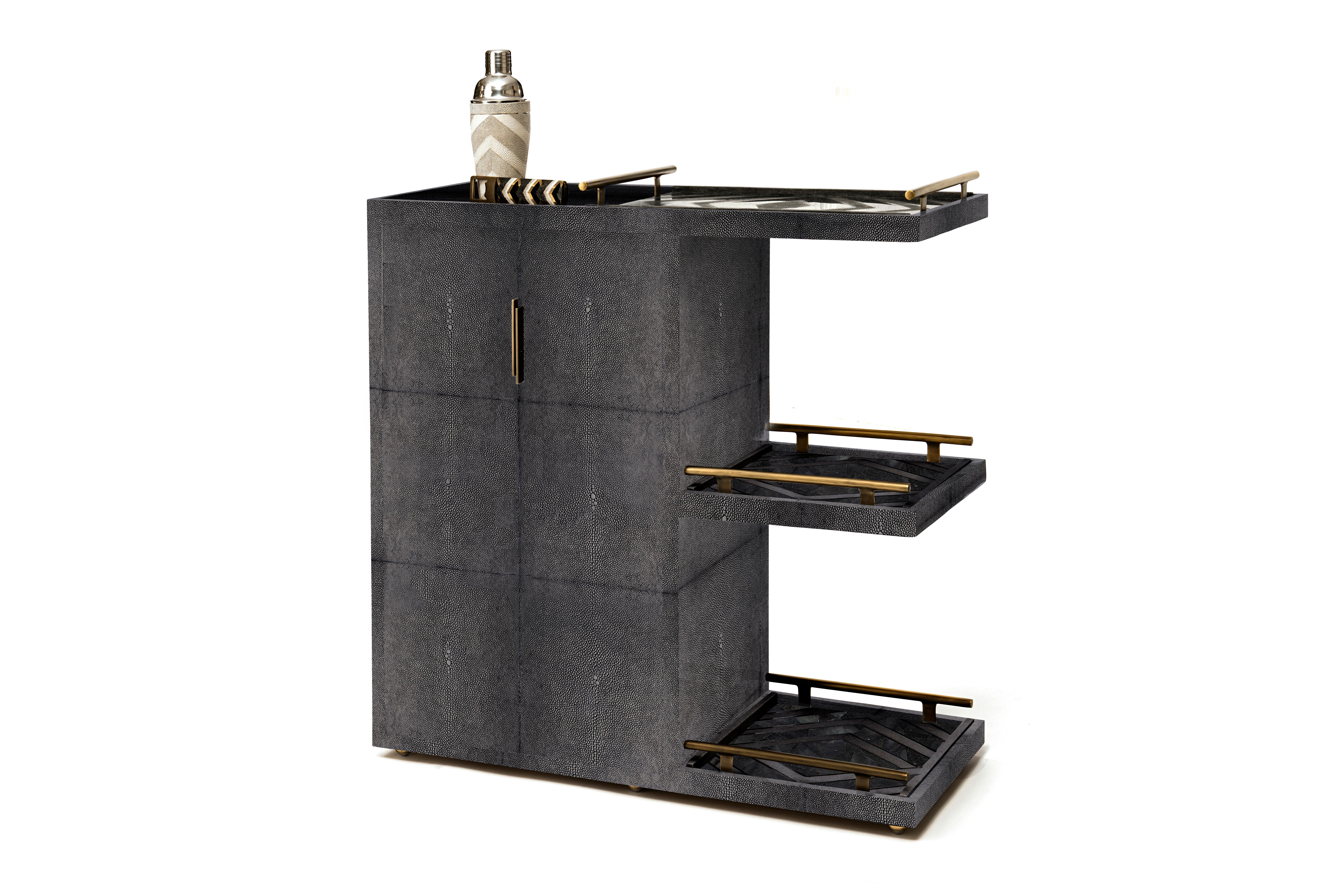 The Kifu Paris bar trolley in cream shagreen with bronze-patina brass details is a luxurious accent piece for any living space. This piece can be easily moved on invisible wheels and comes with three removable trays, in zig zag black shagreen/shell.