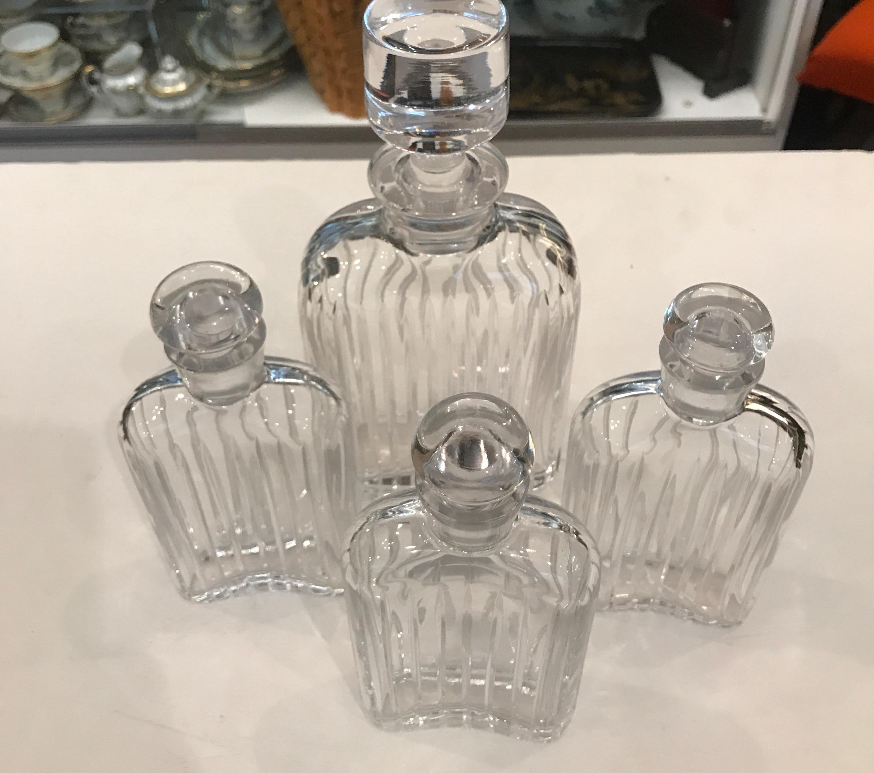 Four crystal decanters one large and three smaller in the form of flasks. The crystal bottle form with three shaped like antique style flasks. elegant Art Deco style, the pattern is similar to a Baccarat pattern but no markings on any of them, this