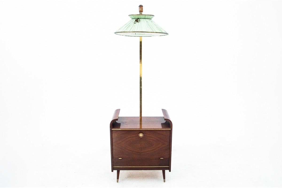 A bar combined with a lamp from the 1970s.

The bar has a door that opens downwards. Inside, there is one space, on the sides of which there are four glass holders. On a slightly curved wooden arm decorated with metal, there is a lamp with a green,