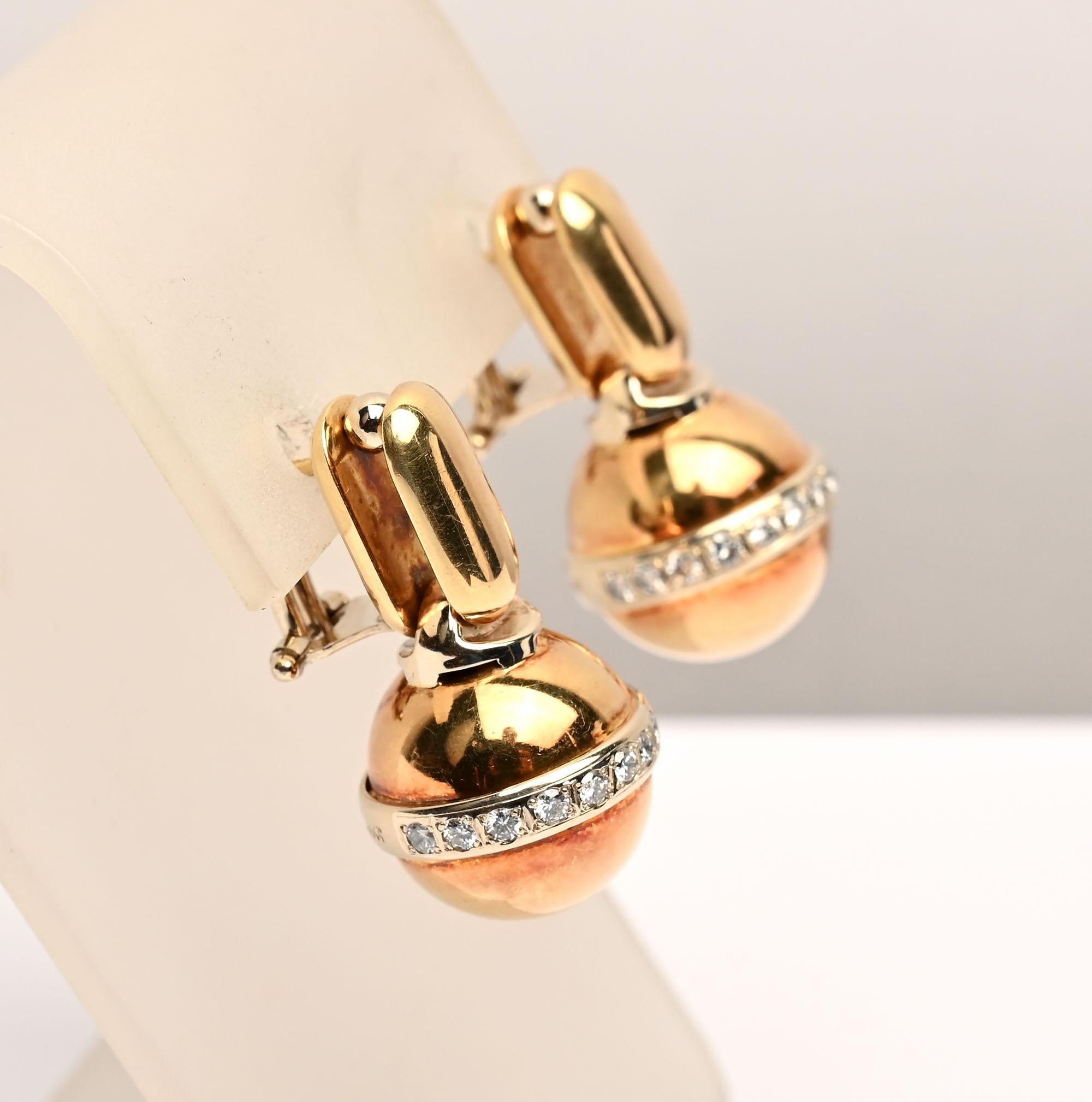 Unusual gold ball earrings suspended by an oval panel. The fold ball is surrounded by diamonds . The ball is a slightly rose gold with the rest of the earring made of yellow gold. They are 18 karat. Backs are posts and clips. 