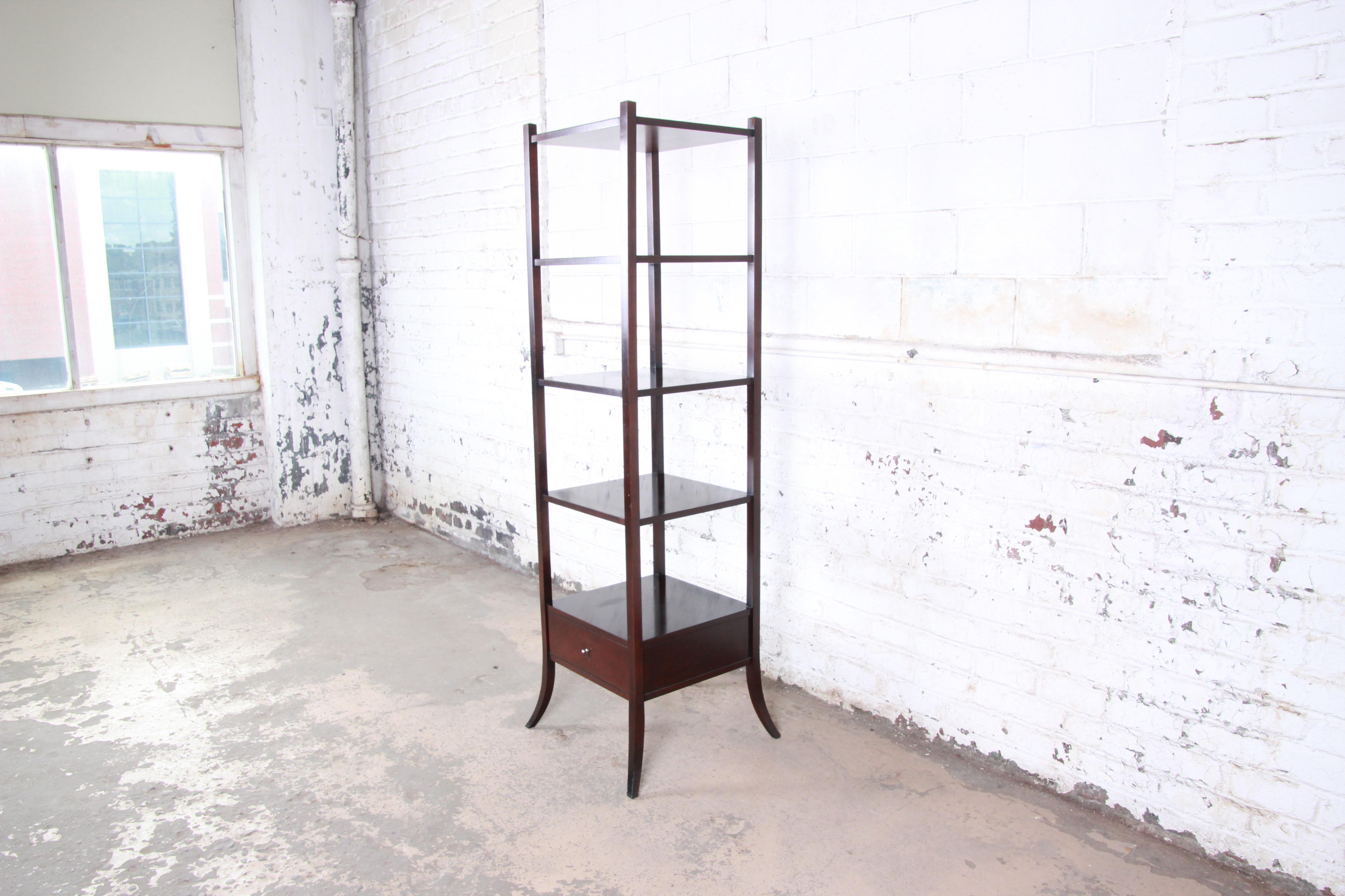 A beautiful dark mahogany étagère designed by Barbara Barry for Baker Furniture. The étagère features clean, simple lines and solid mahogany construction. It offers ample space for storage or display, with four shelves and a single drawer. The