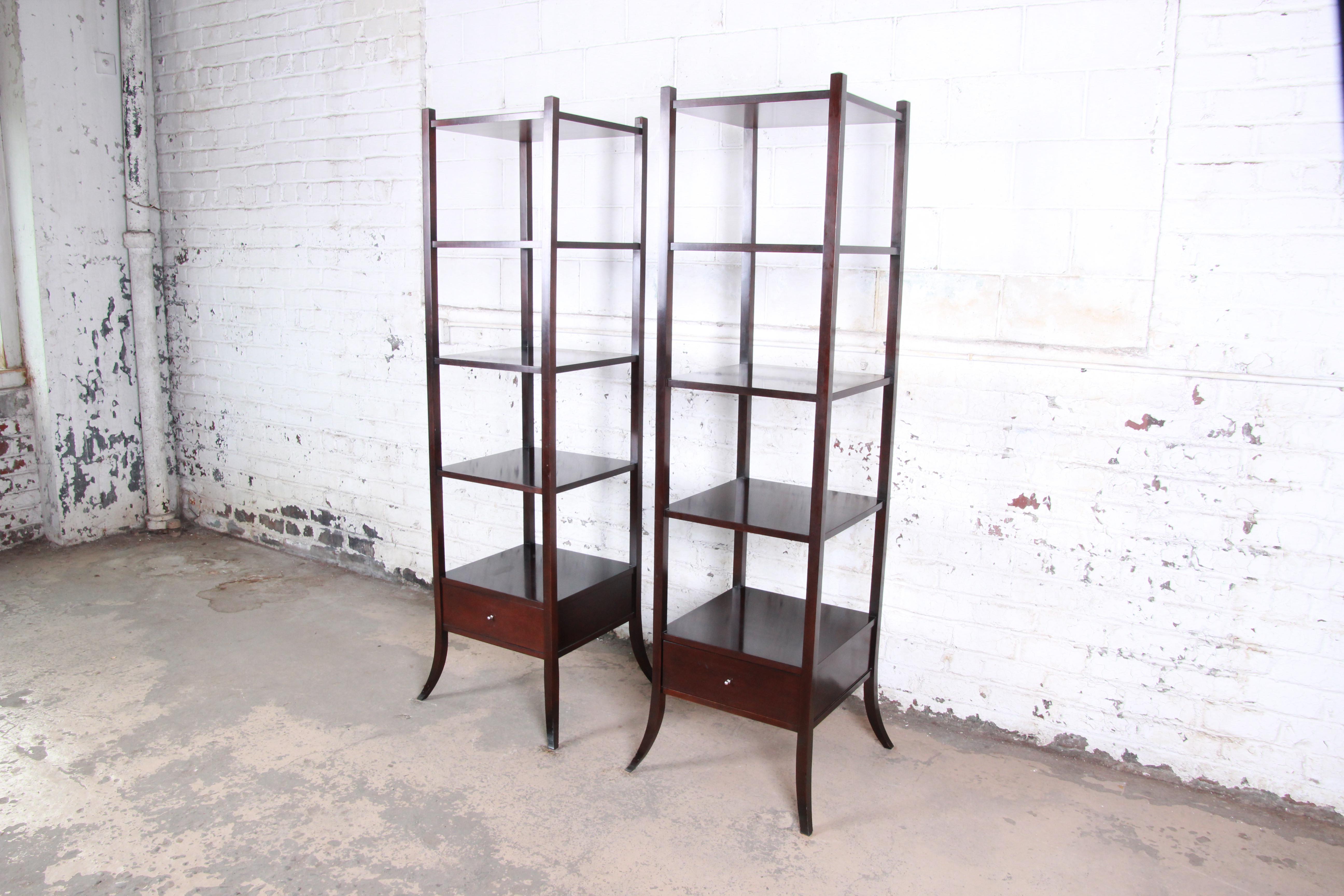 A gorgeous pair of dark mahogany étagères designed by Barbara Barry for Baker Furniture. The etageres feature clean, simple lines and solid mahogany construction. They offer ample space for storage or display, each with four shelves and a single