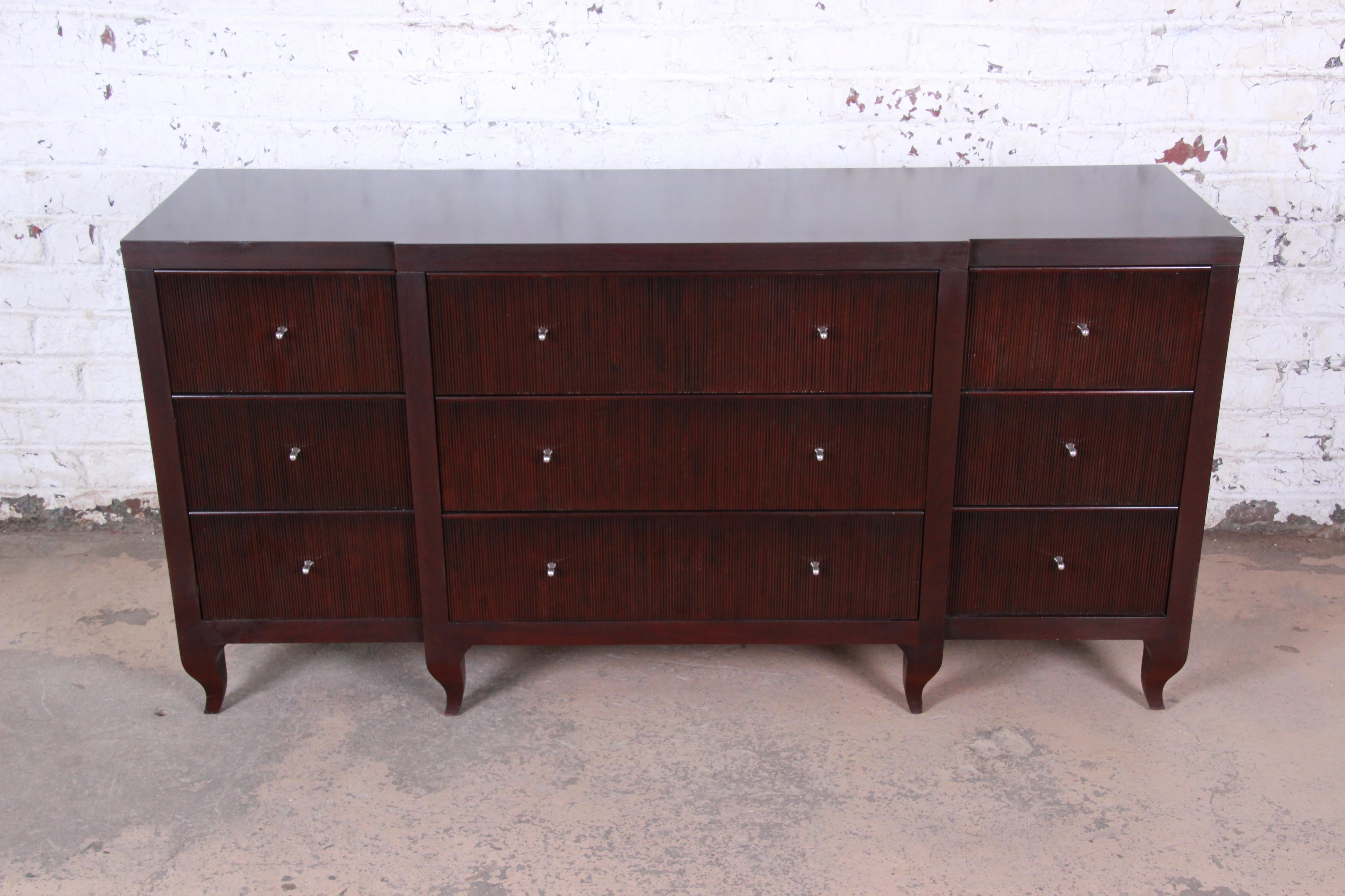 An exceptional dark mahogany triple dresser or credenza designed by Barbara Barry for Baker Furniture. The dresser features beautiful mahogany wood grain with a unique vertical fluted design on the drawer fronts. It offers ample storage, with nine