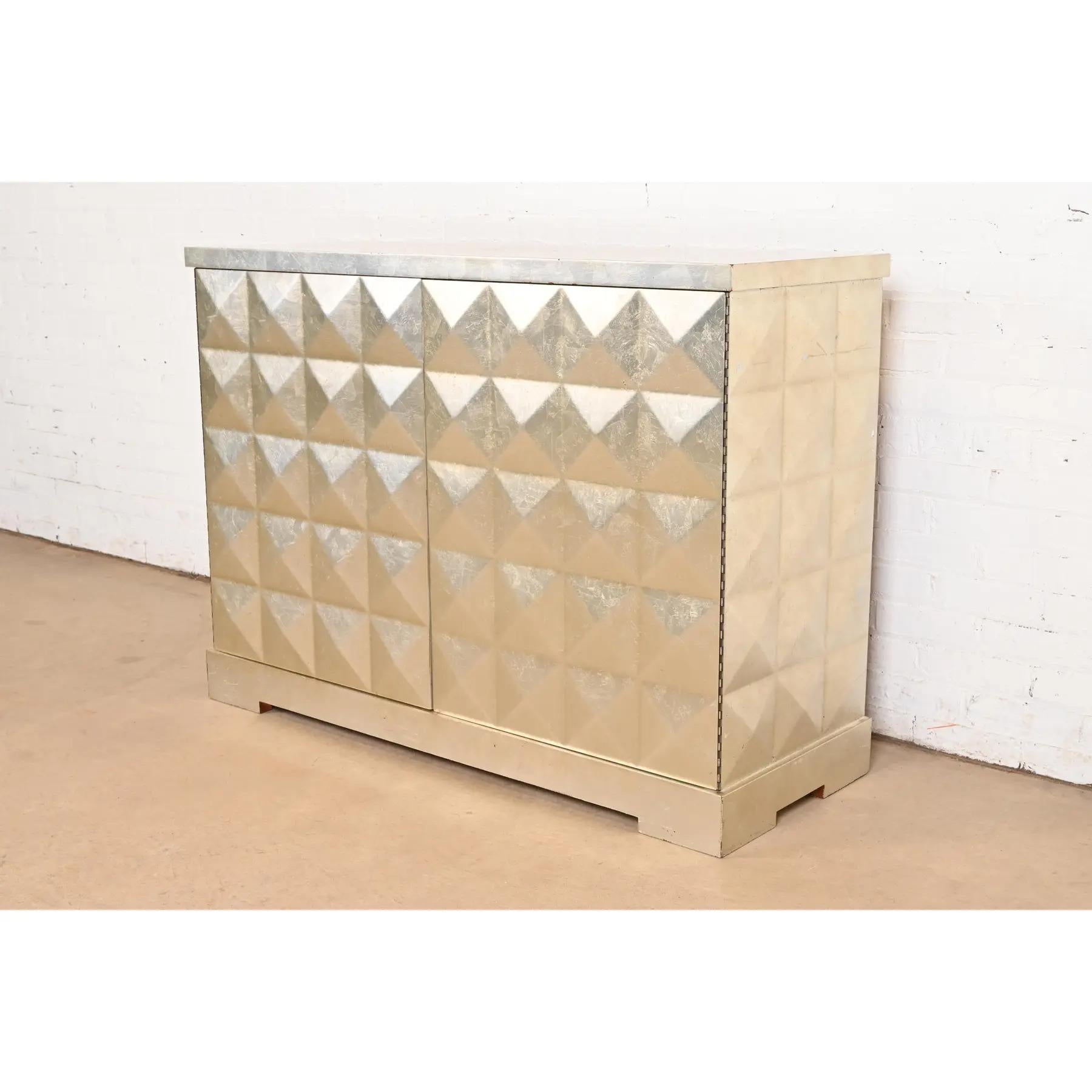 An outstanding modern Hollywood Regency style diamond faceted sideboard or bar cabinet

By Barbara Barry for Baker Furniture

USA, Circa 1990s

Silver leaf finish, with diamond faceted front and sides, and red lacquered interior. Shelves are