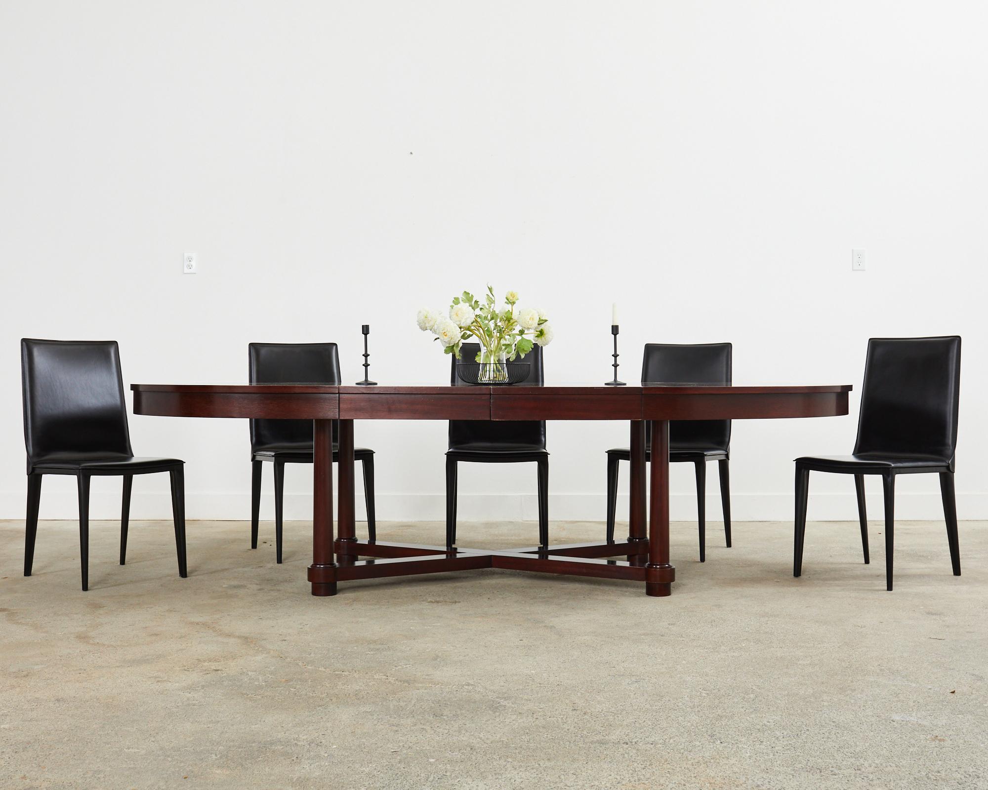 Imposing Barbara Barry collection for Baker Furniture modern neoclassical style extending dining table. Crafted from mahogany featuring an oval top that measures 68 inches wide closed and 108 inches wide with two 20 inch leaves installed. Supported