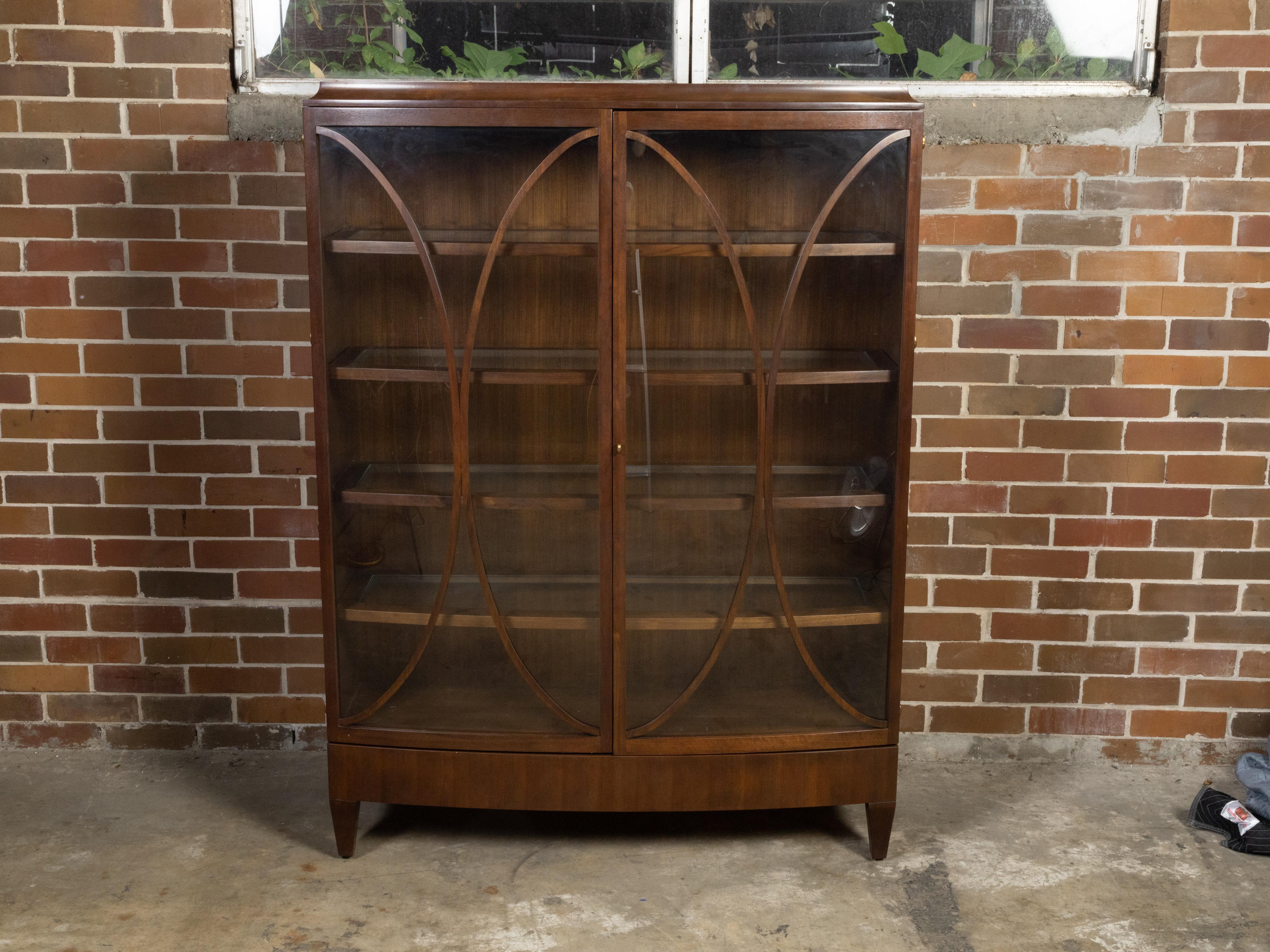 A Barbara Barry for Henredon wooden bow front vitrine cabinet from the late 20th century with oval motifs, glass doors and glass shelves. Designed by Barbara Barry for Henredon during the later years of the 20th century, this wooden cabinet features